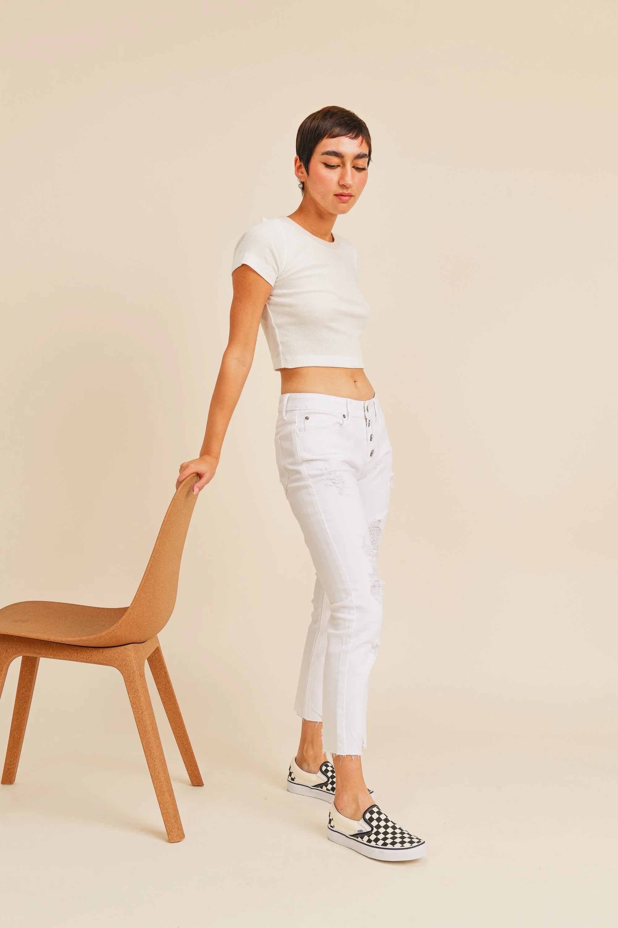 Woman wearing a white outfit with checkered shoes against a beige background