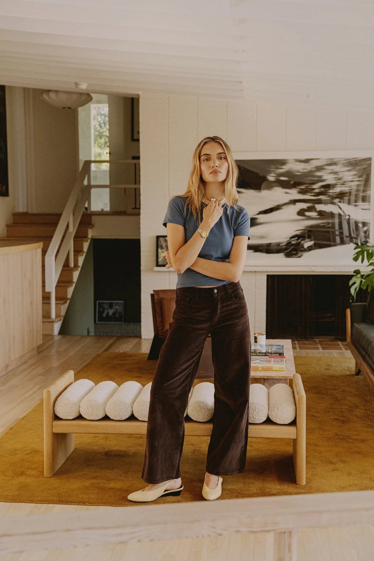 Woman standing in a modern living room with a large painting on the wall.