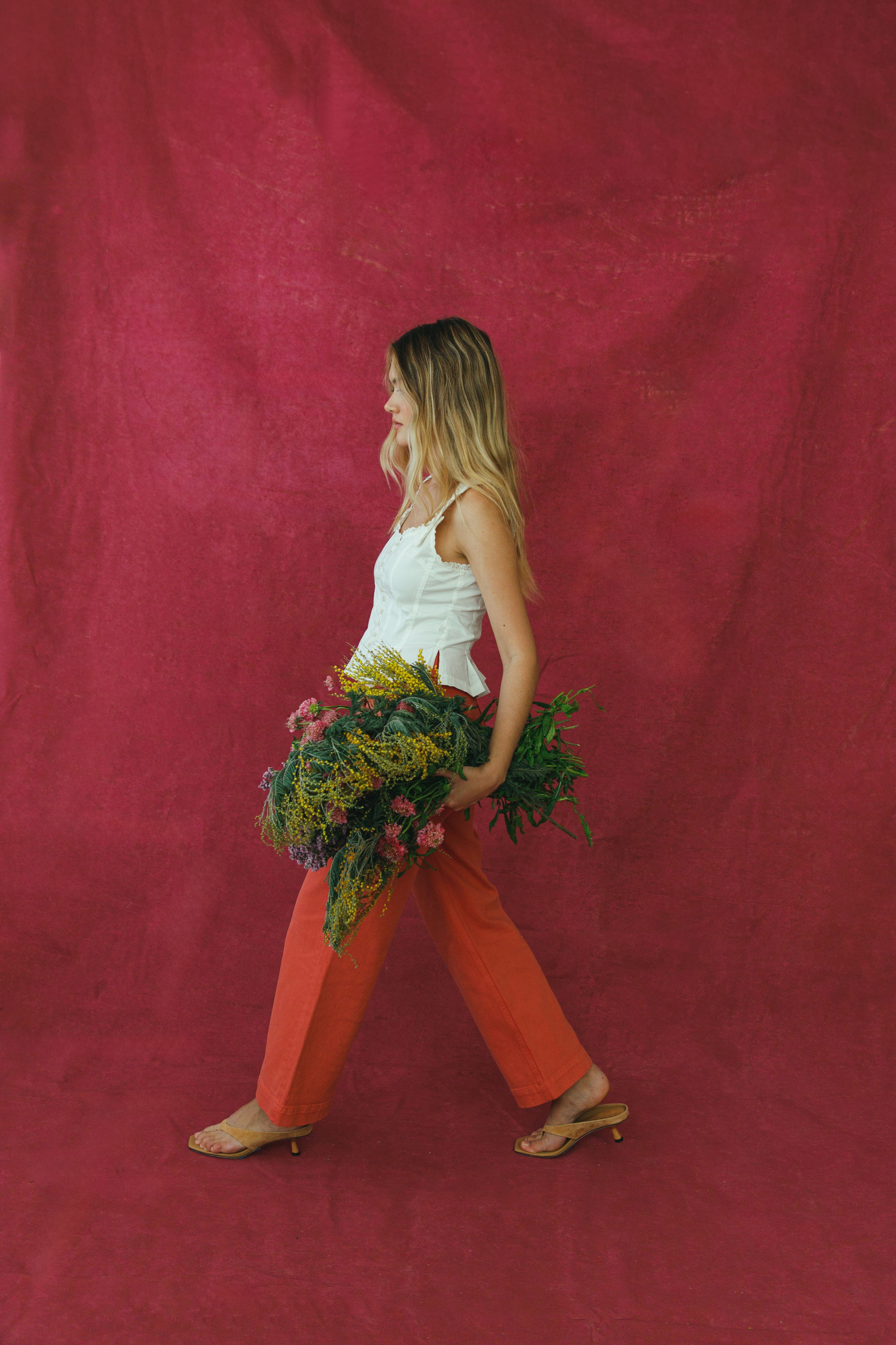 Woman holding a bouquet of flowers against a red background