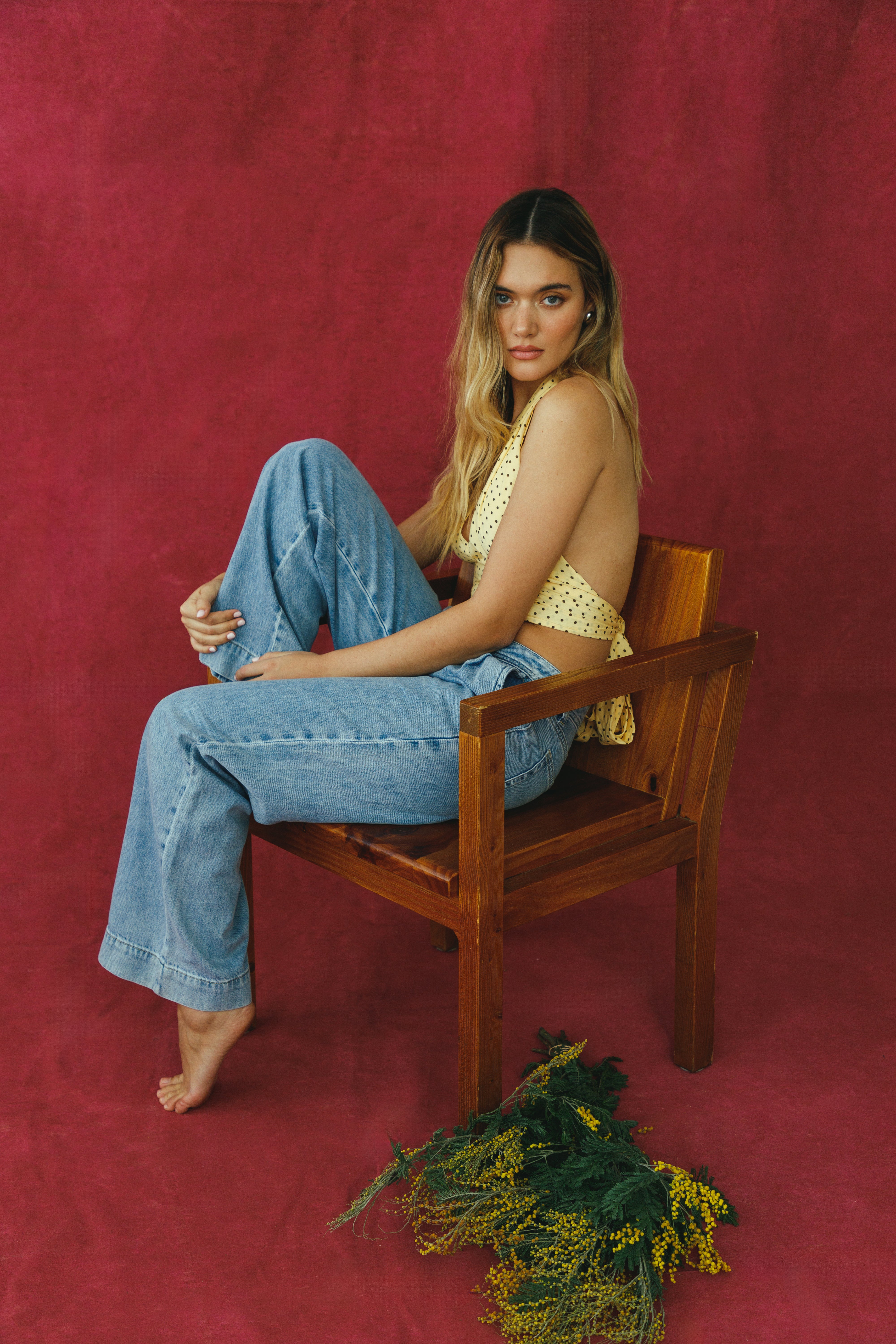 Woman sitting on a wooden chair against a red background