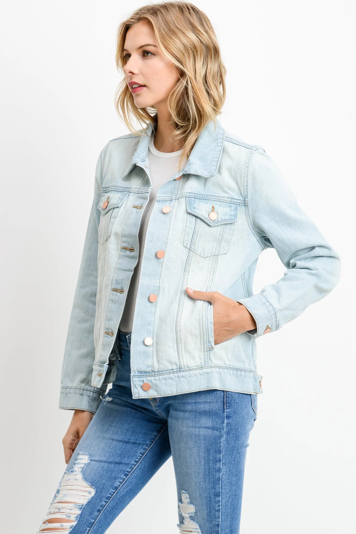Woman wearing a light blue denim jacket and jeans on a white background