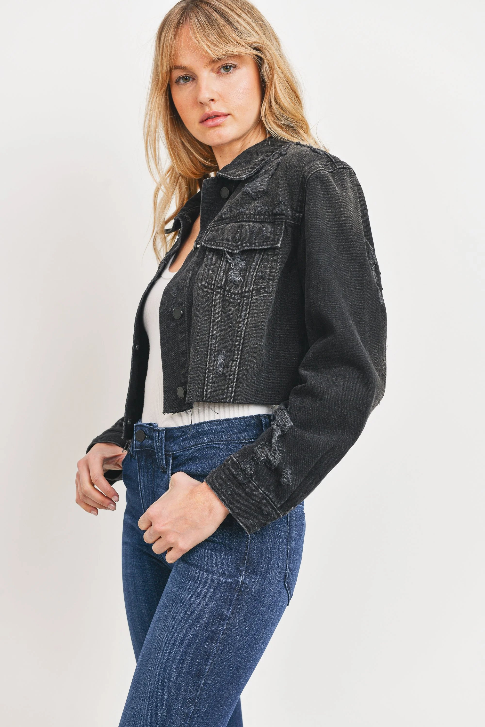 Woman wearing a black denim jacket and blue jeans on a white background