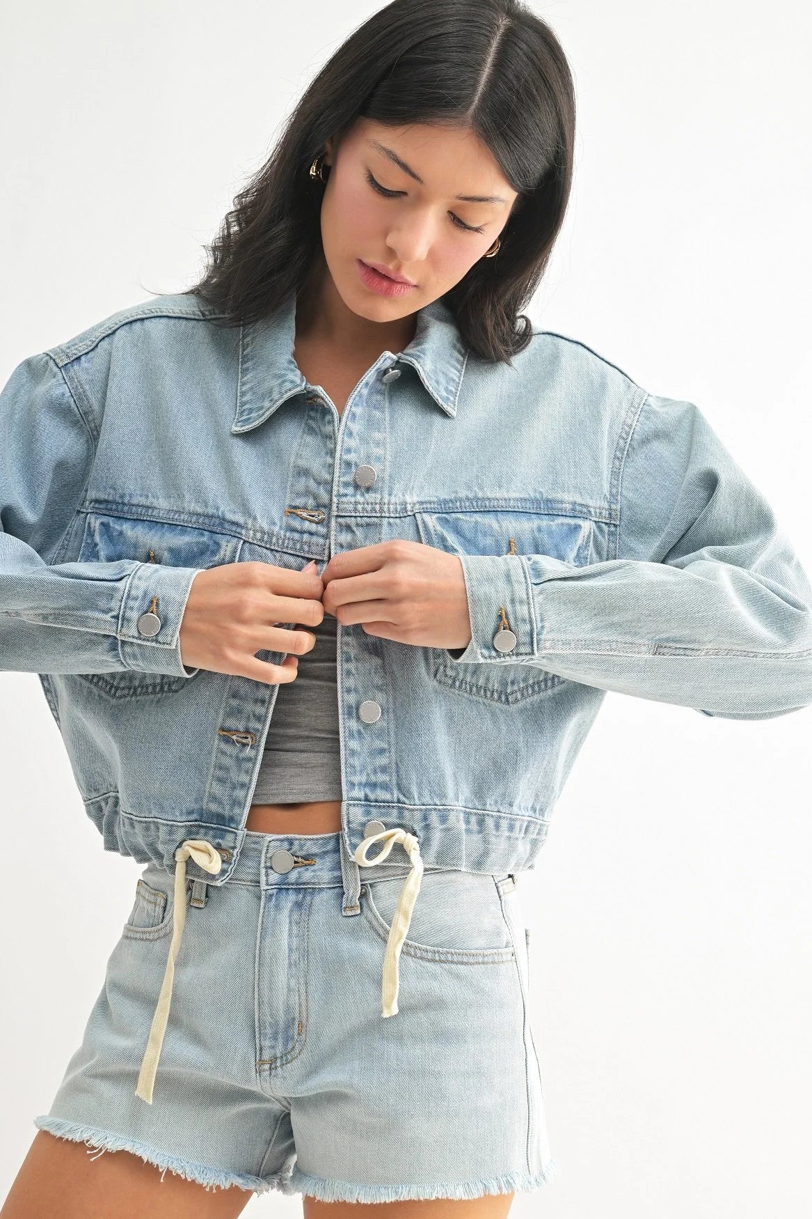 Woman wearing a light blue denim jacket and shorts on a white background