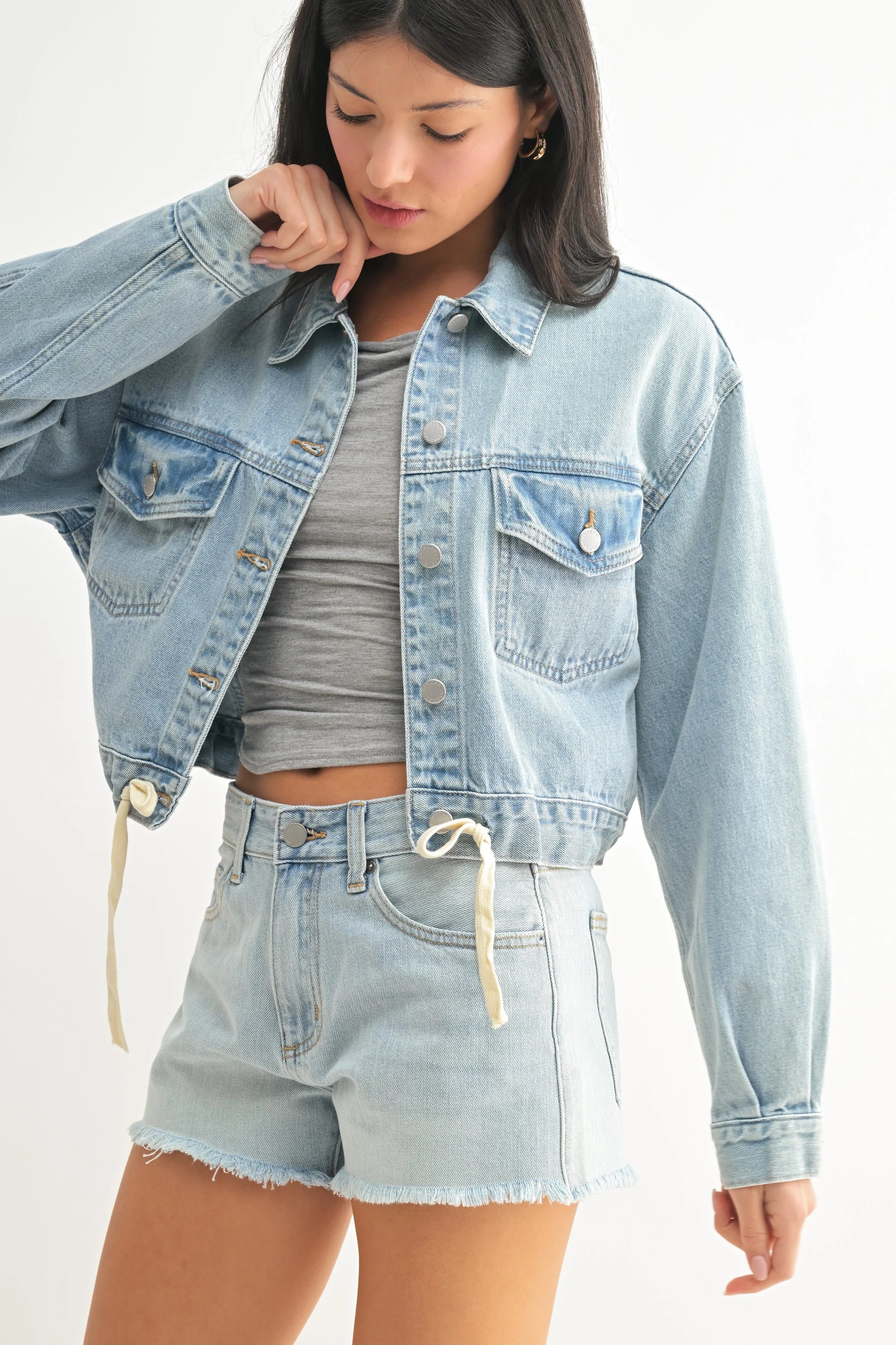 Woman wearing a light blue denim jacket and shorts on a white background