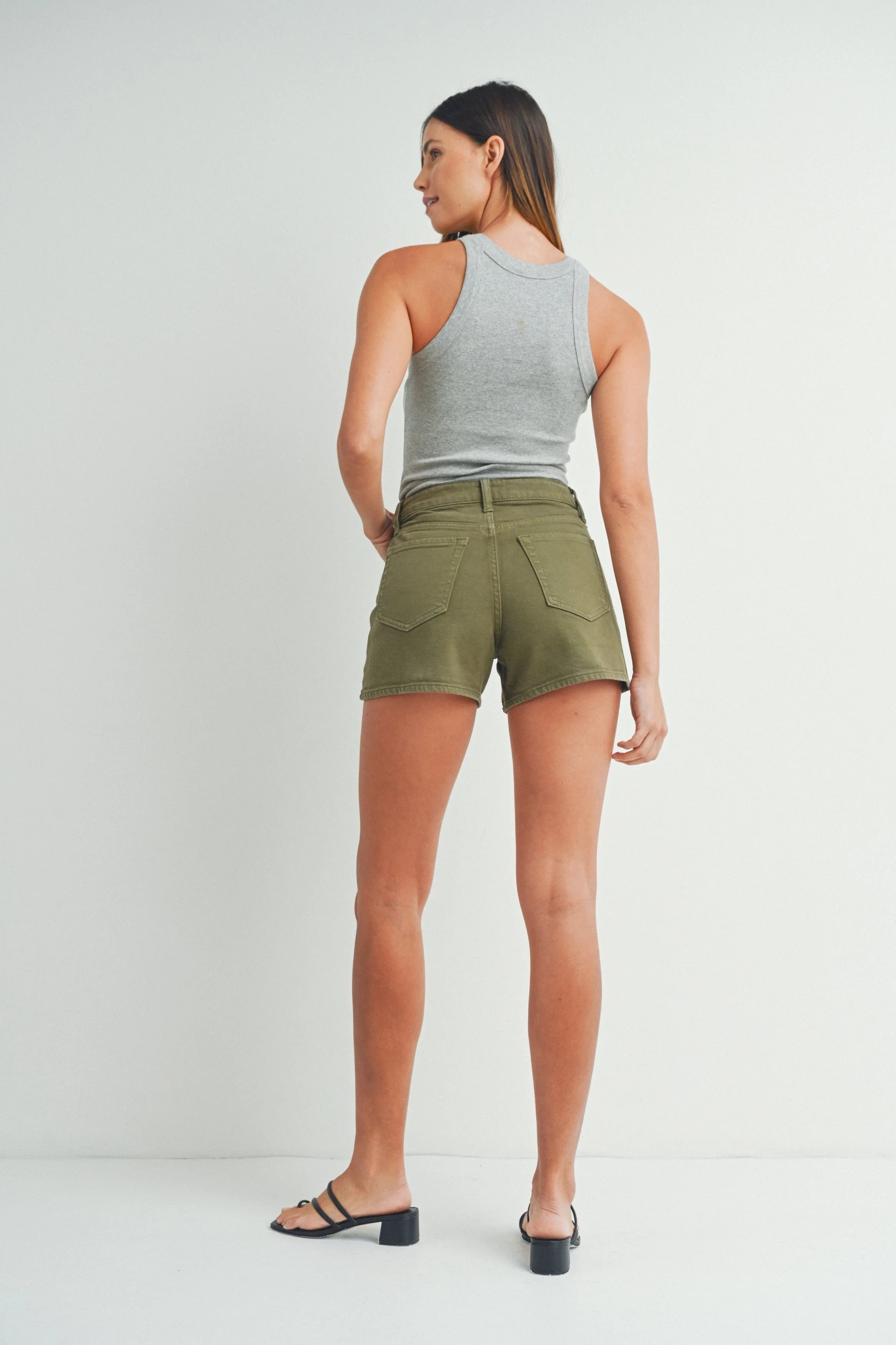 Woman wearing green shorts and a gray tank top on a white background