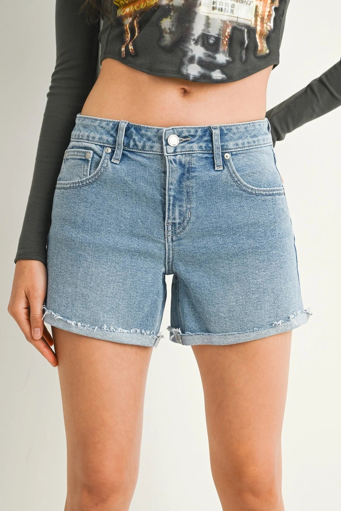 Denim shorts worn by a person on a plain background
