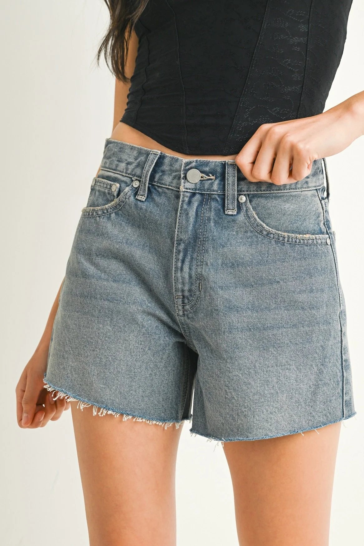 Denim shorts worn by a person on a plain background