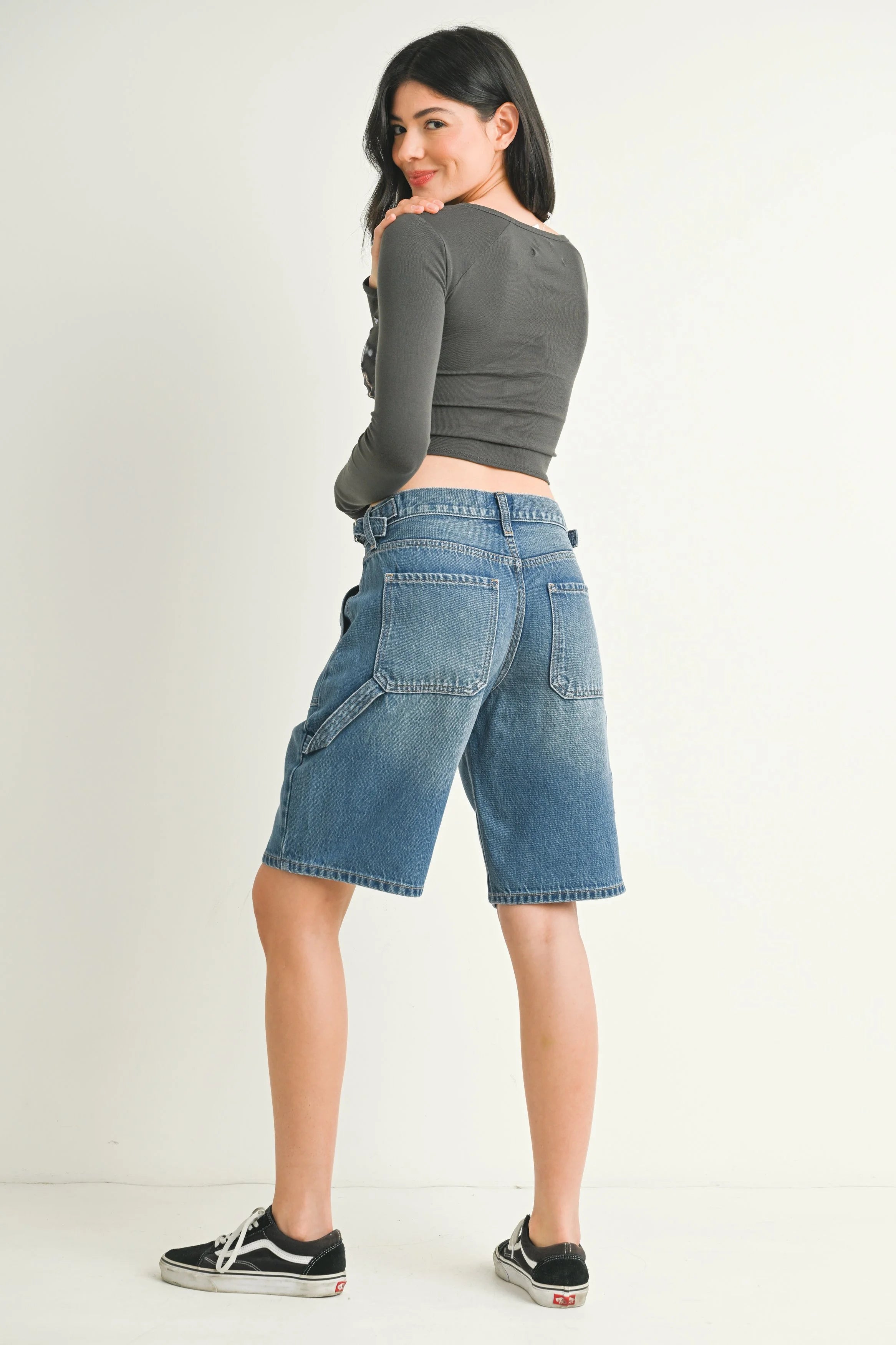 Woman wearing a gray crop top and blue denim shorts on a white background