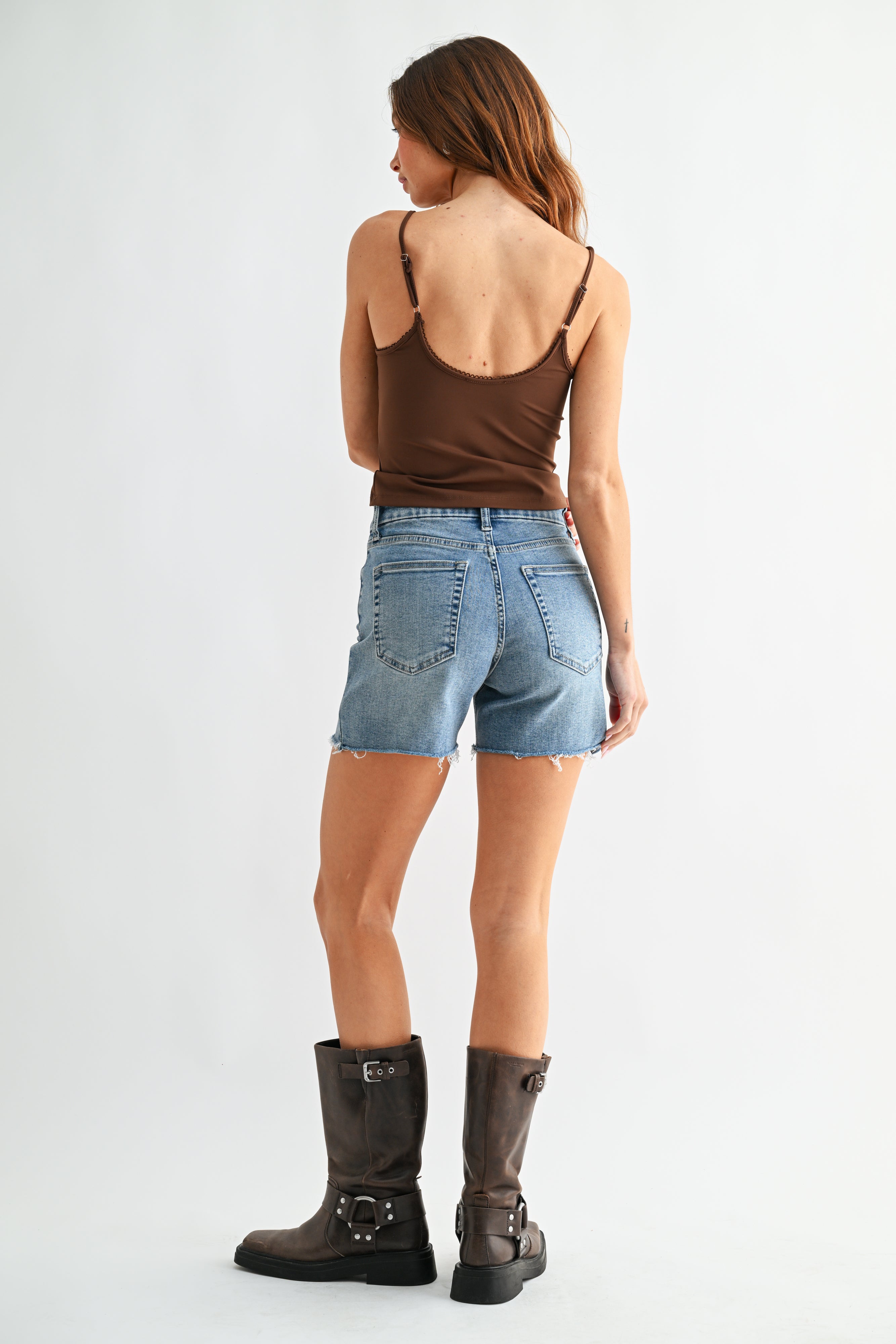 Woman wearing denim shorts and brown boots on a white background