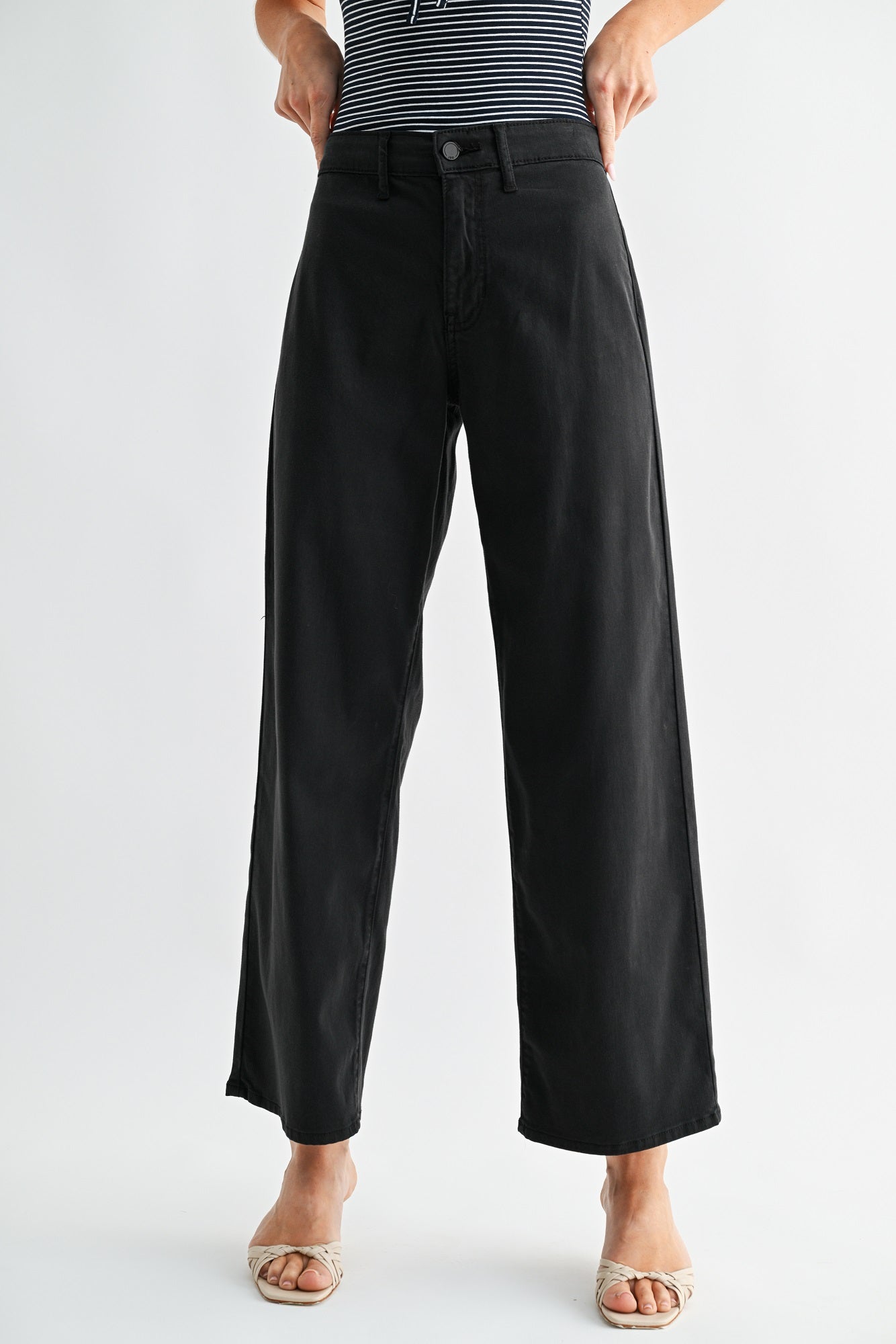 Person wearing black wide-leg pants on a white background