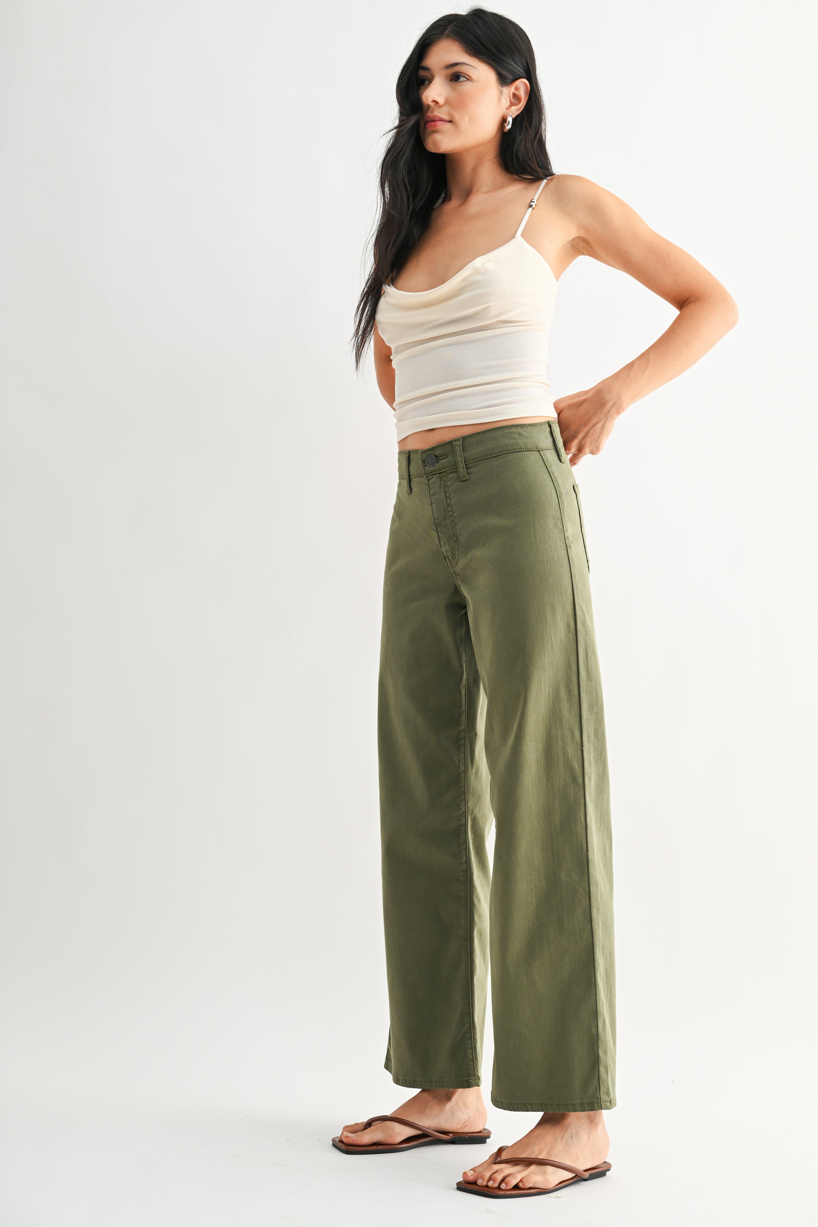 Woman wearing a white top and green pants on a white background