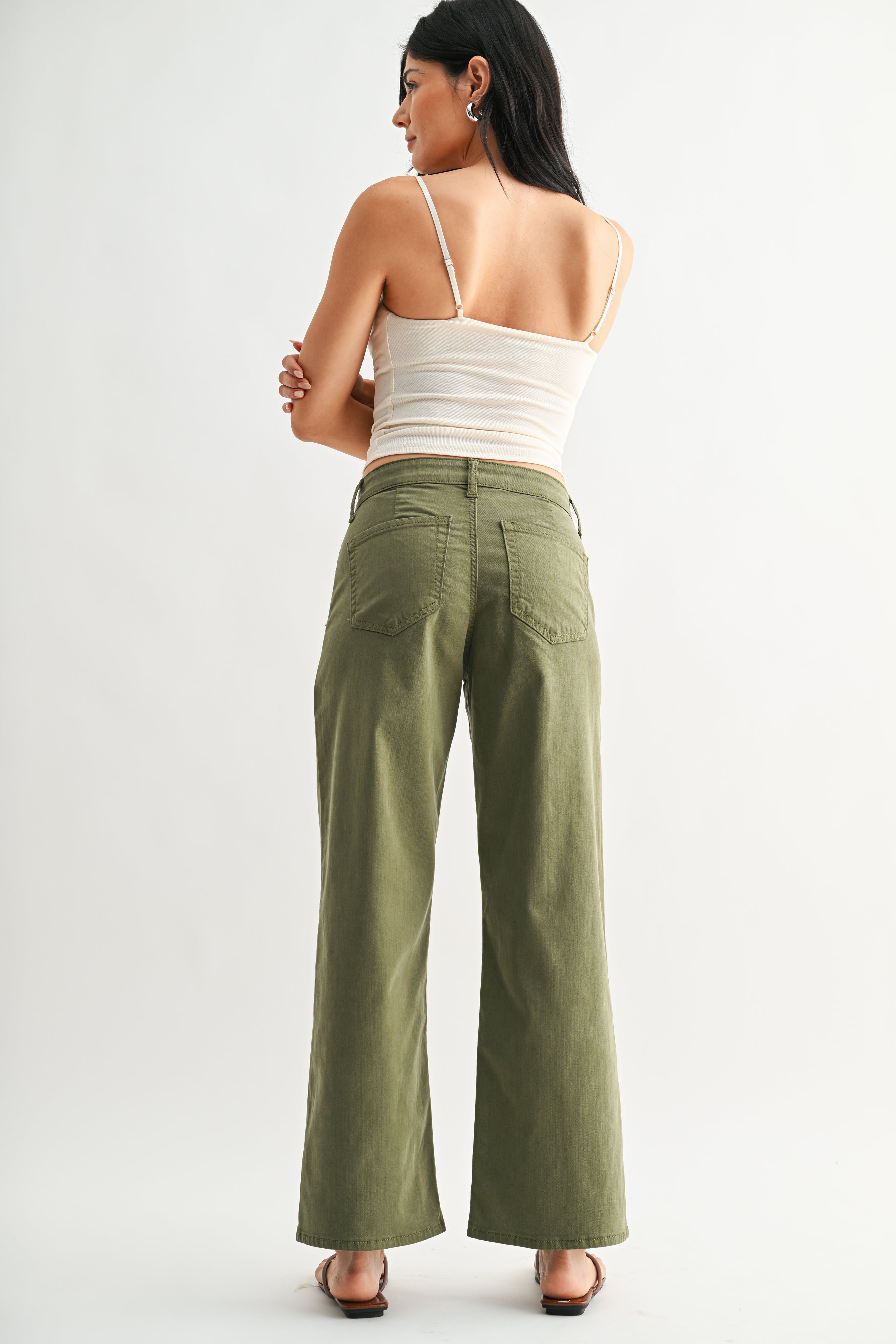 Woman wearing a white top and green pants on a white background