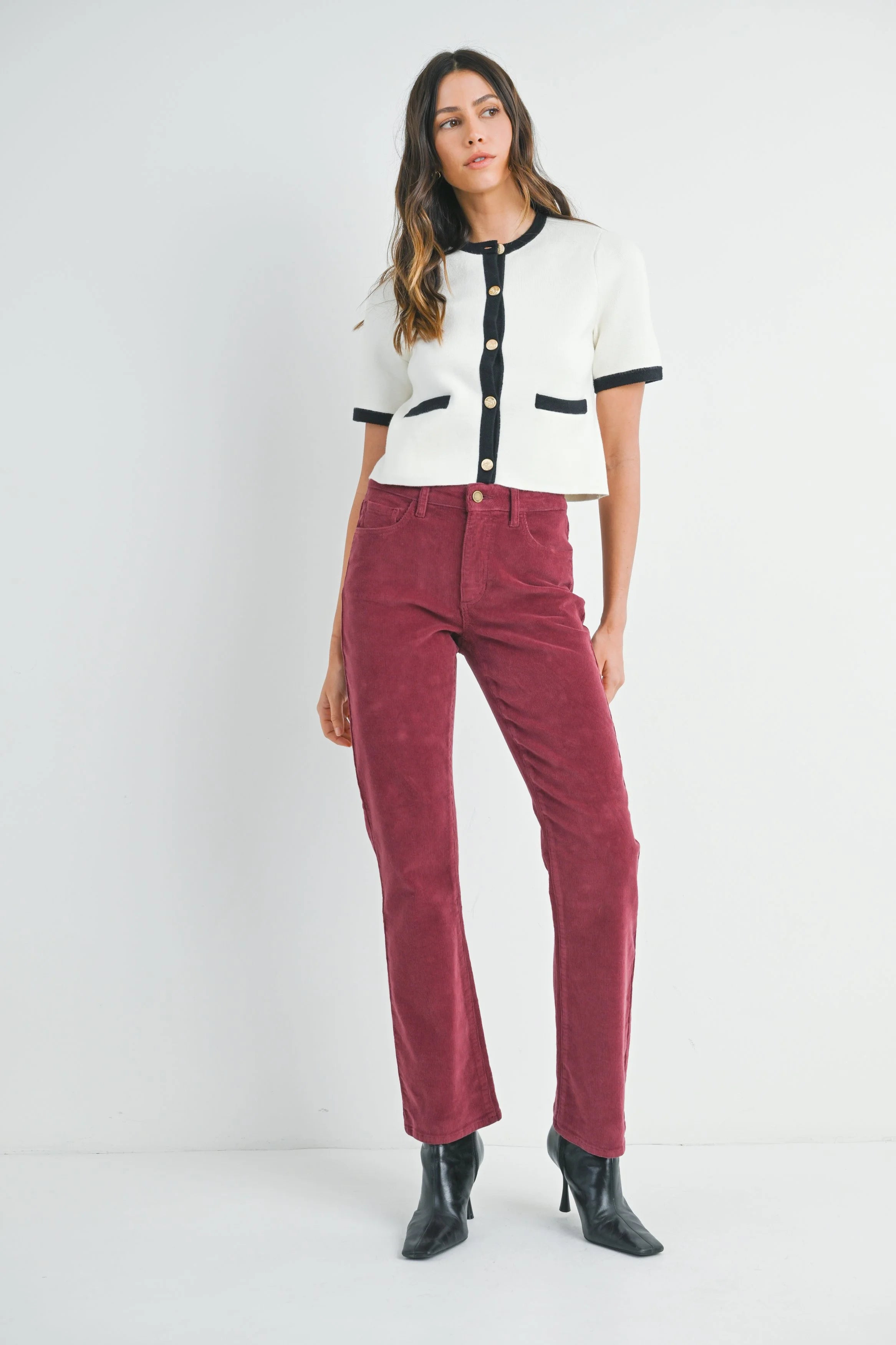 Woman wearing a white and black top with red pants on a white background
