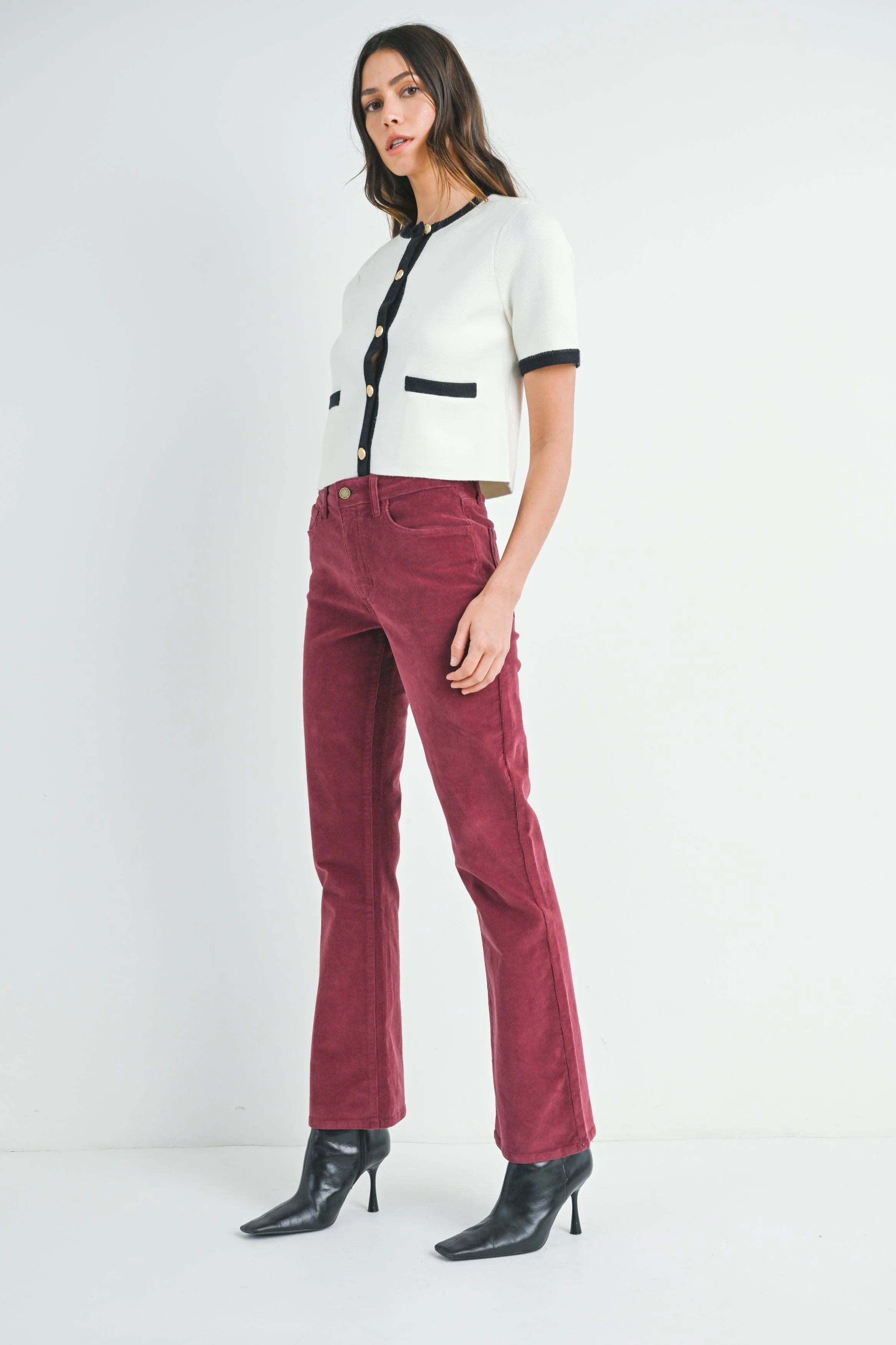 Woman wearing a white and black top with red pants on a white background