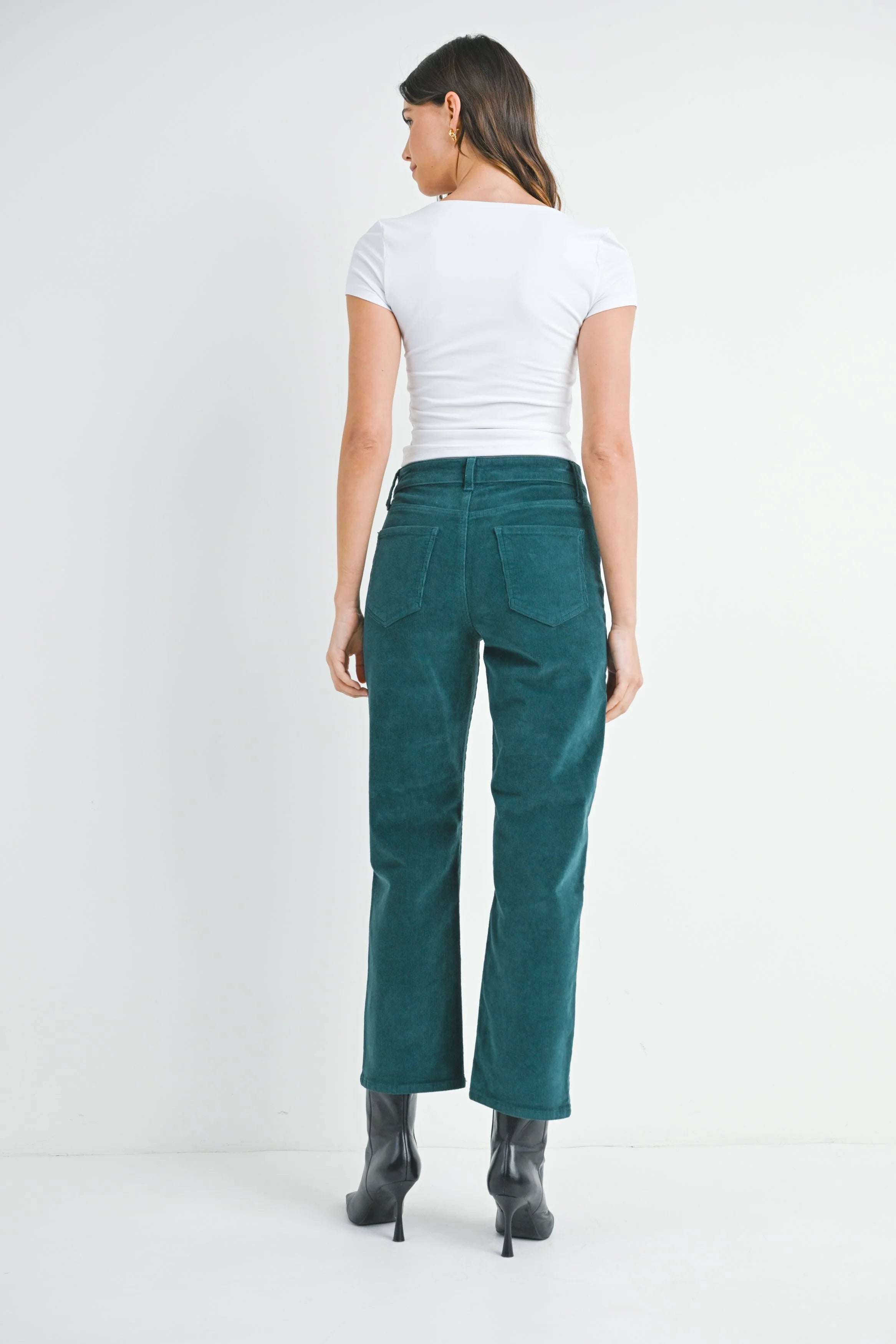 Person wearing teal pants and a white top on a white background