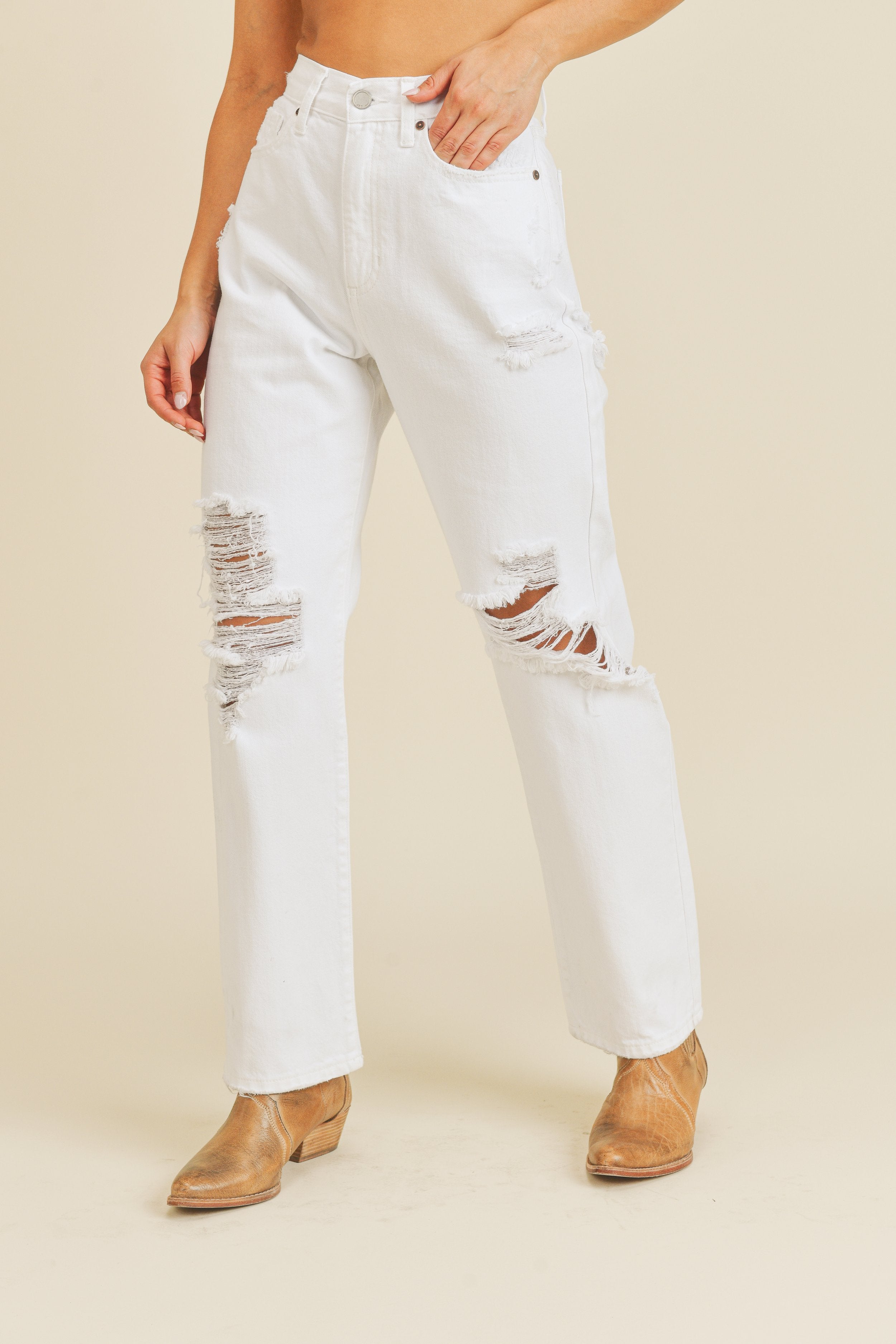 White distressed jeans worn by a person on a beige background