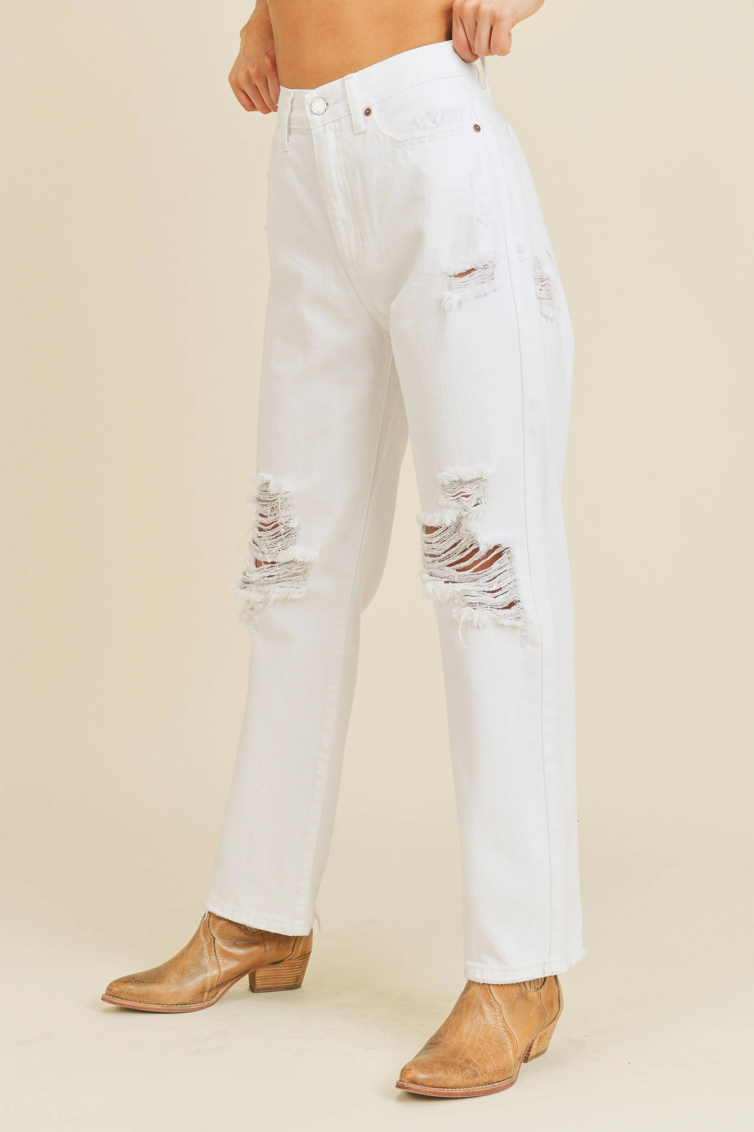 White distressed jeans worn by a person on a beige background