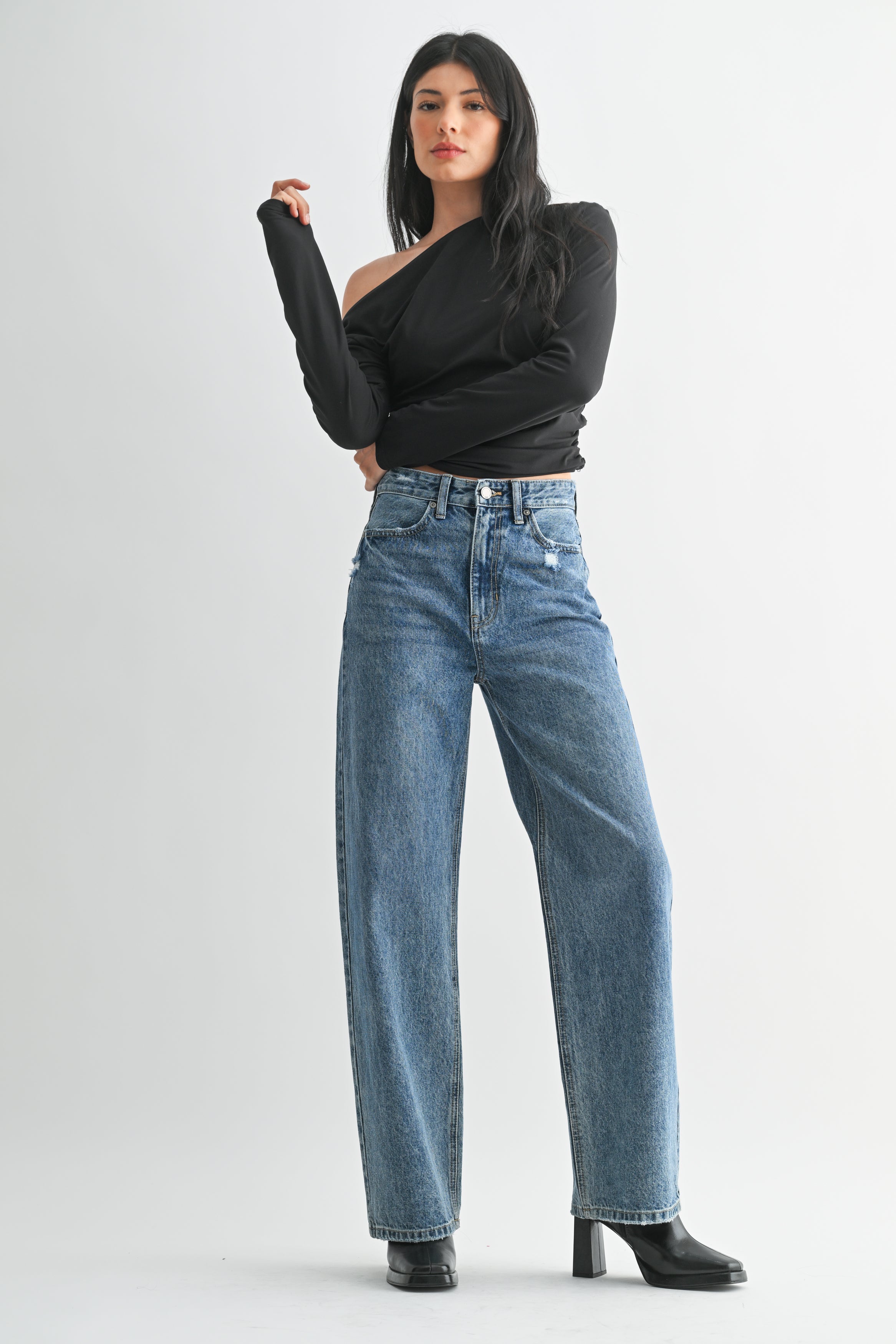 Woman wearing a black top and blue jeans on a white background