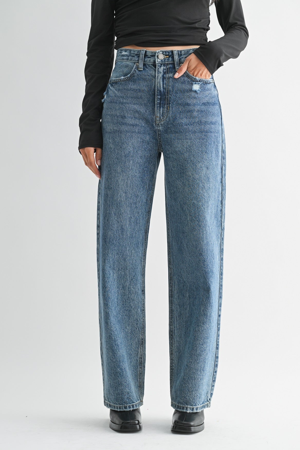 Person wearing blue jeans on a plain background