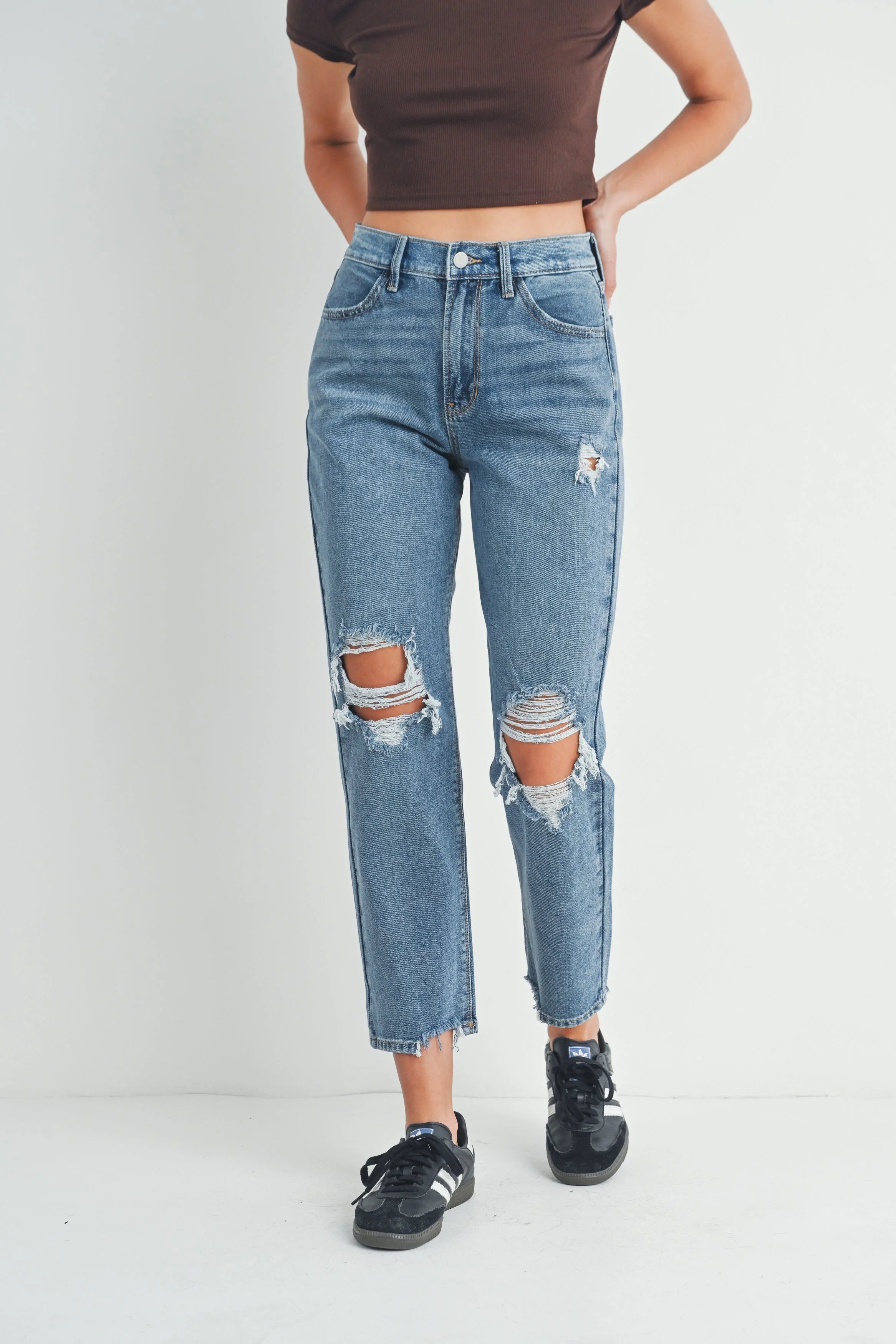 Person wearing distressed blue jeans on a white background