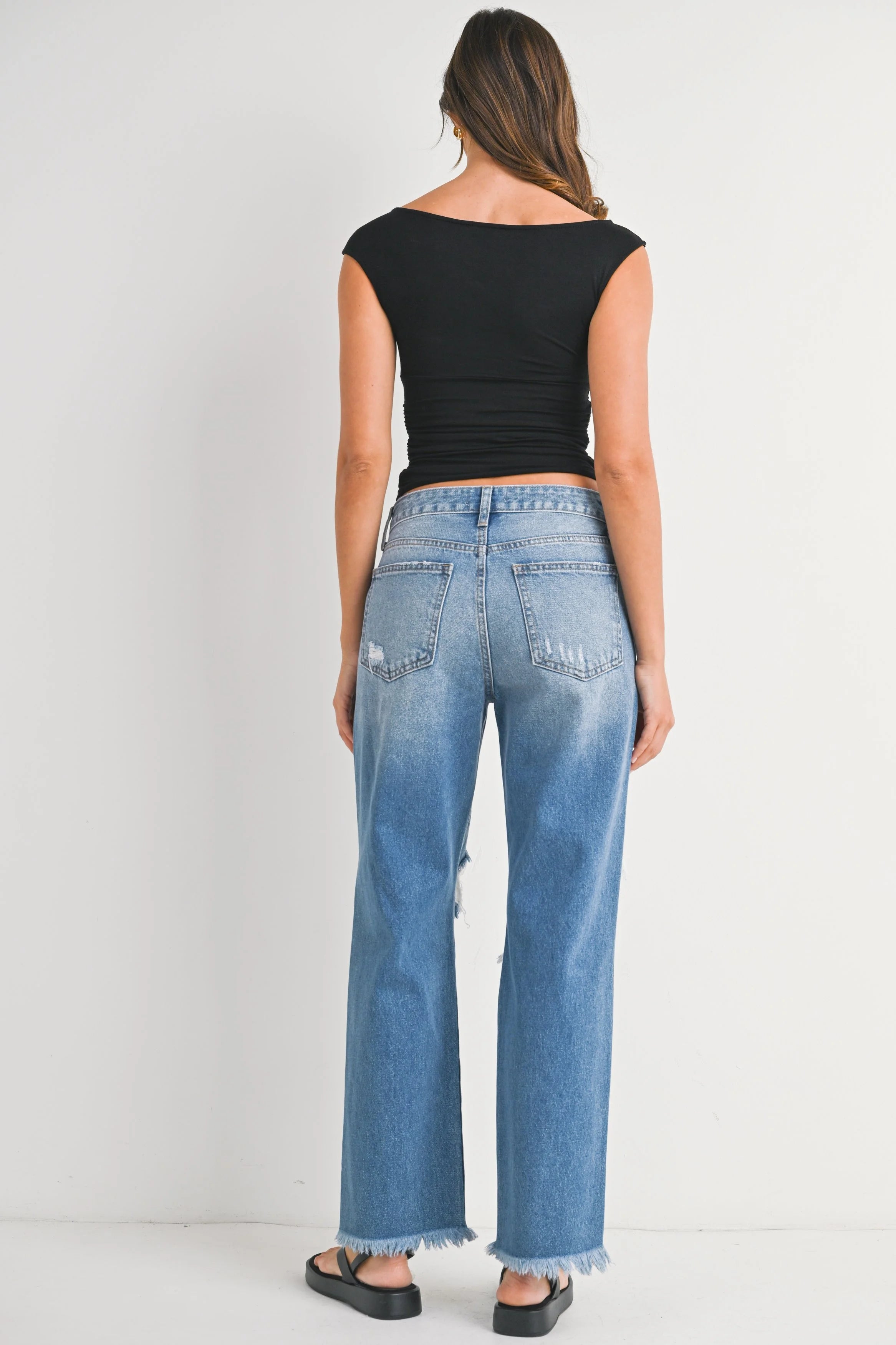 Woman wearing blue jeans and a black top on a white background