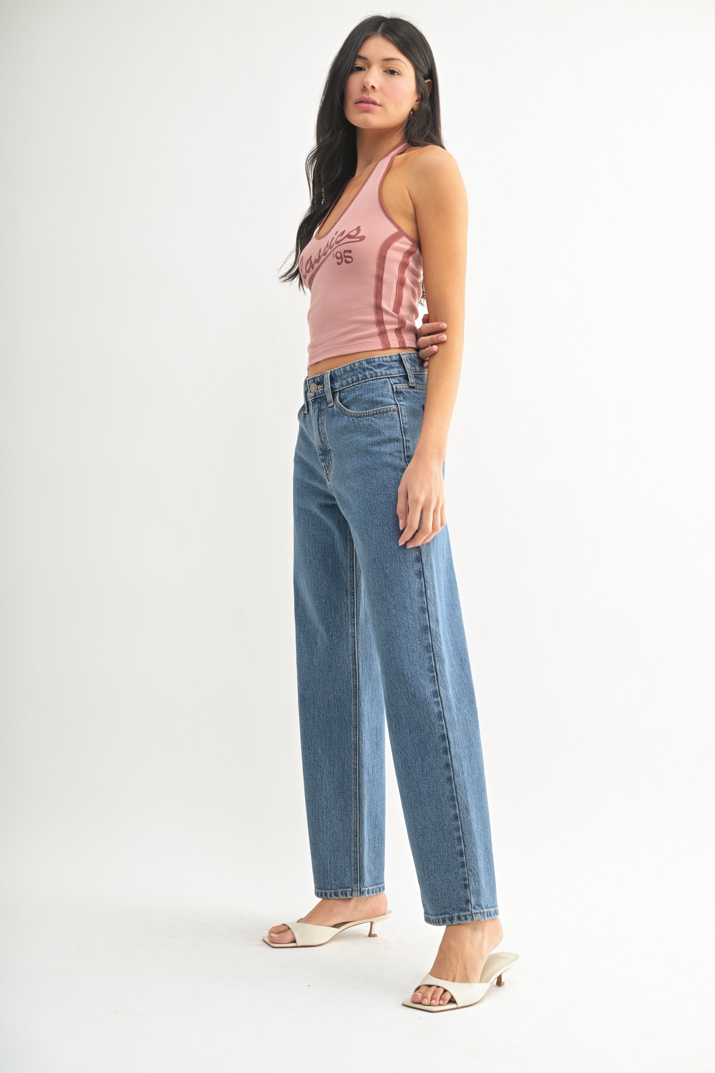 Woman wearing a pink tie-dye top and blue jeans on a white background