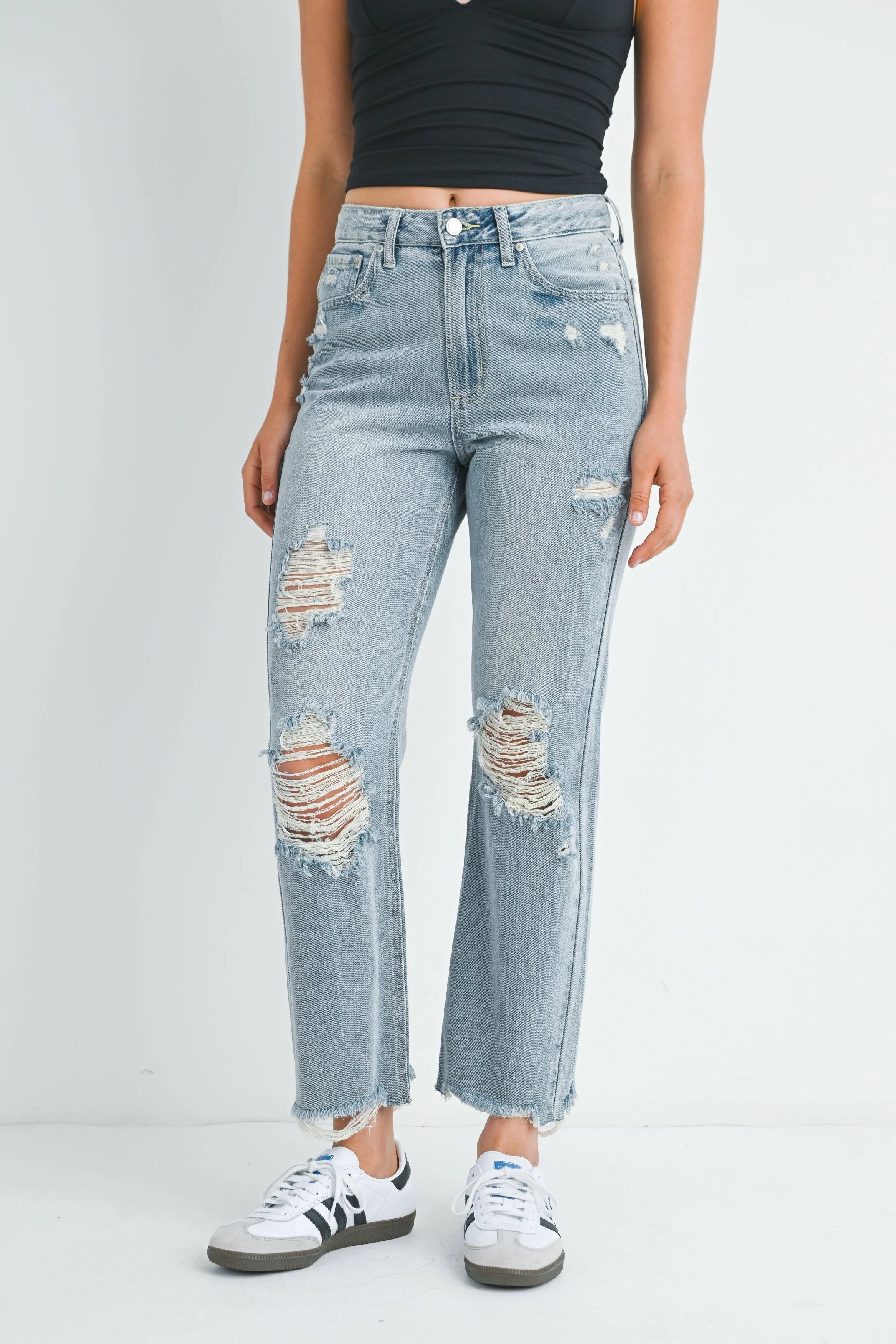 Person wearing light blue distressed jeans on a white background