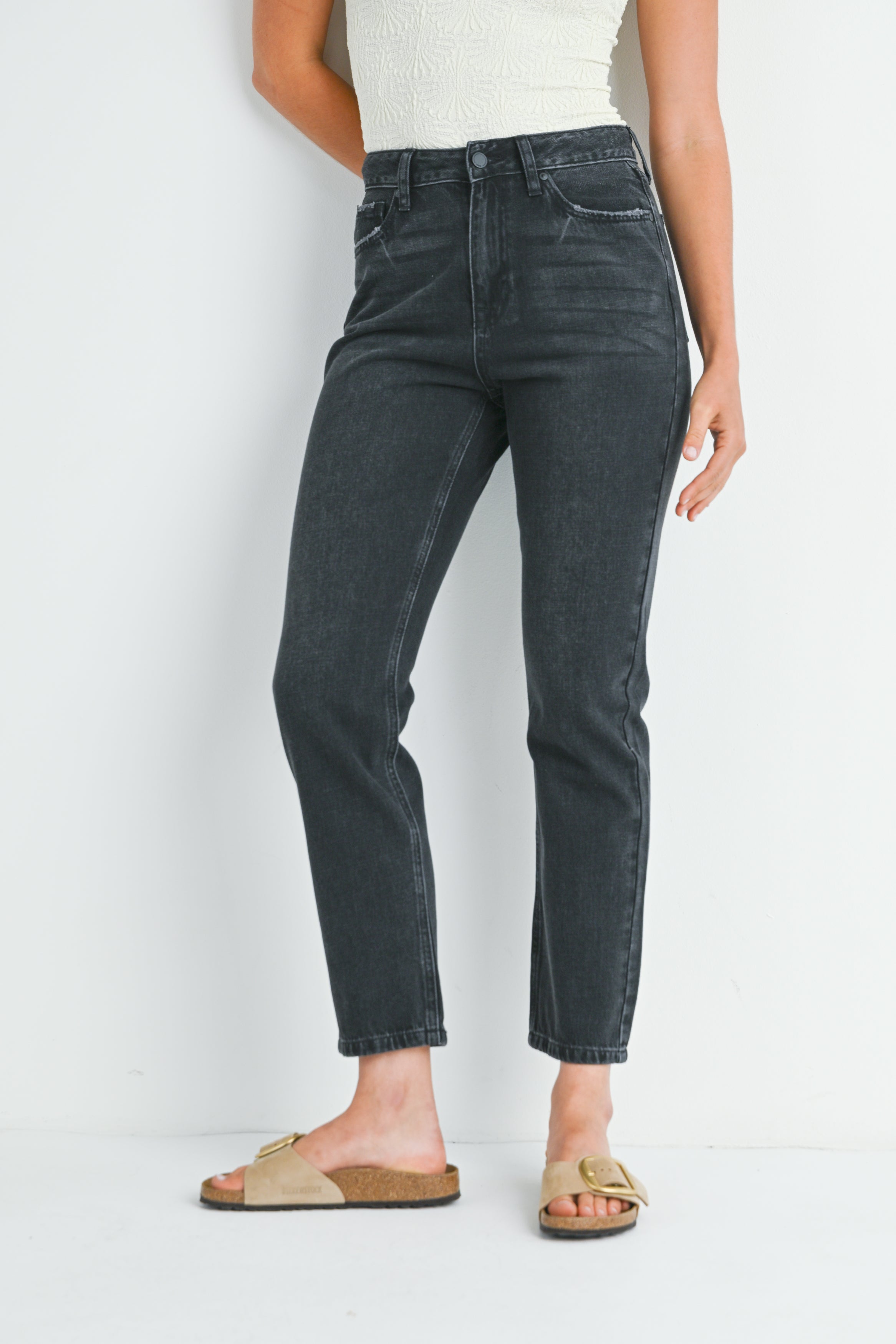 Person wearing black jeans and sandals on a white background