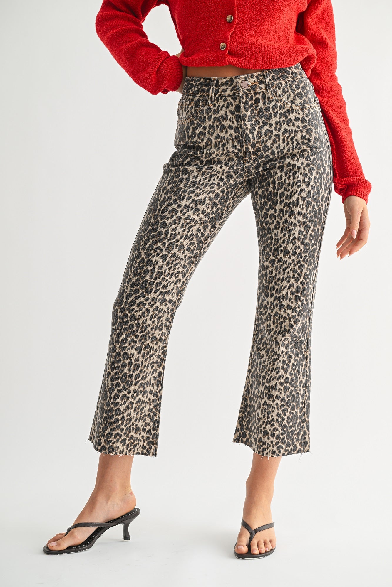 Person wearing leopard print pants and a red cardigan on a white background