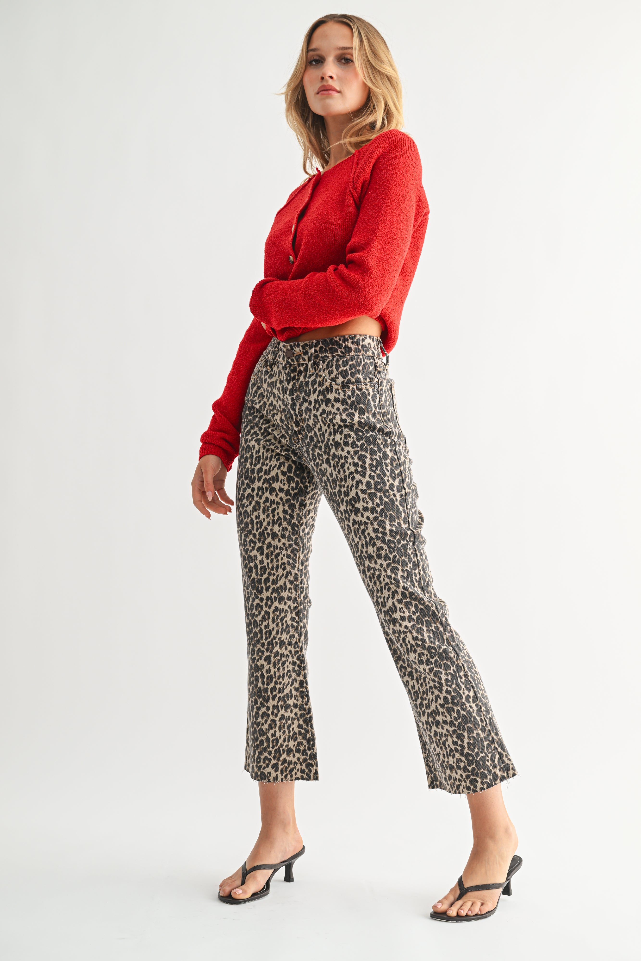 Woman wearing a red sweater and patterned pants on a white background