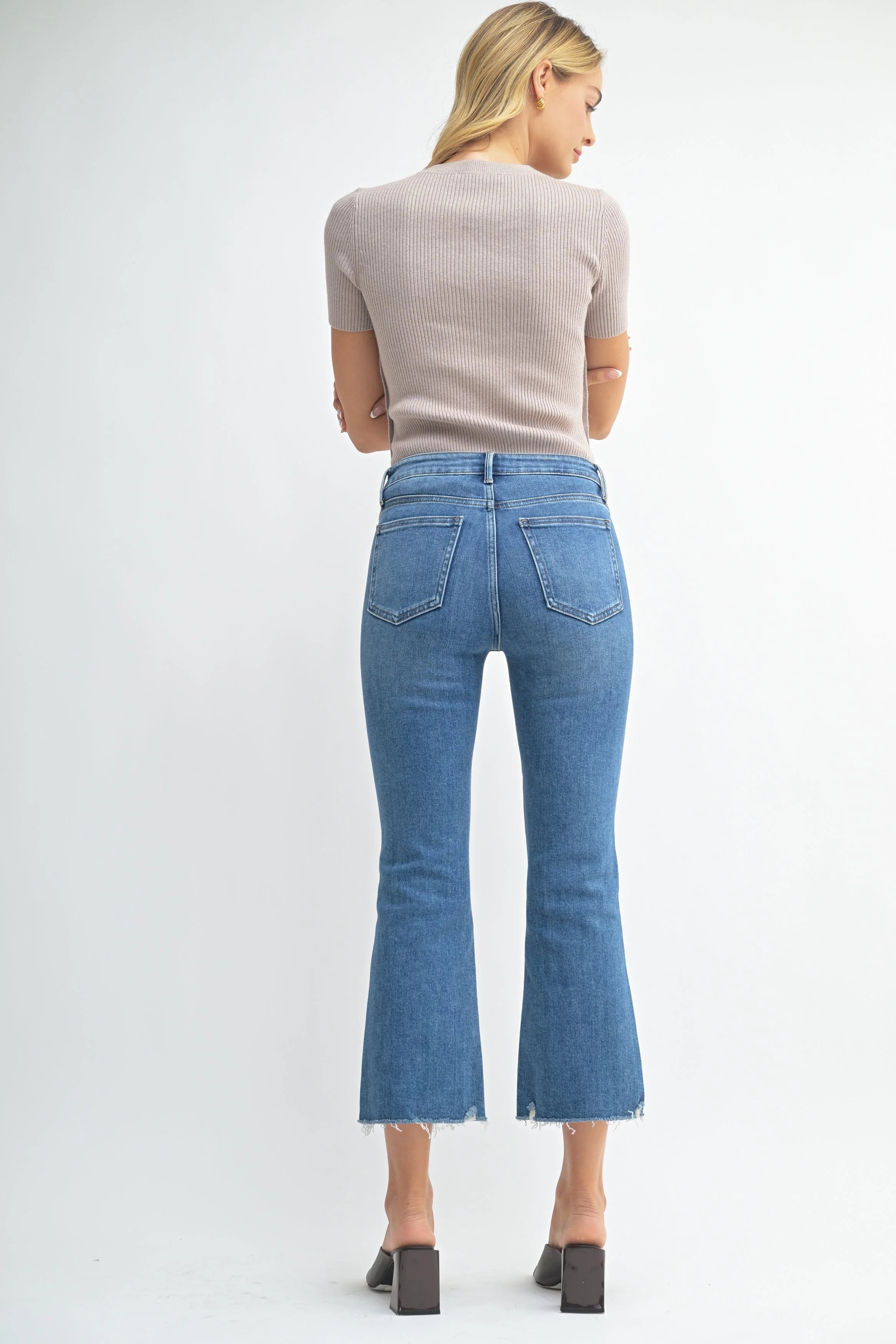 Woman wearing blue jeans and a beige top on a white background