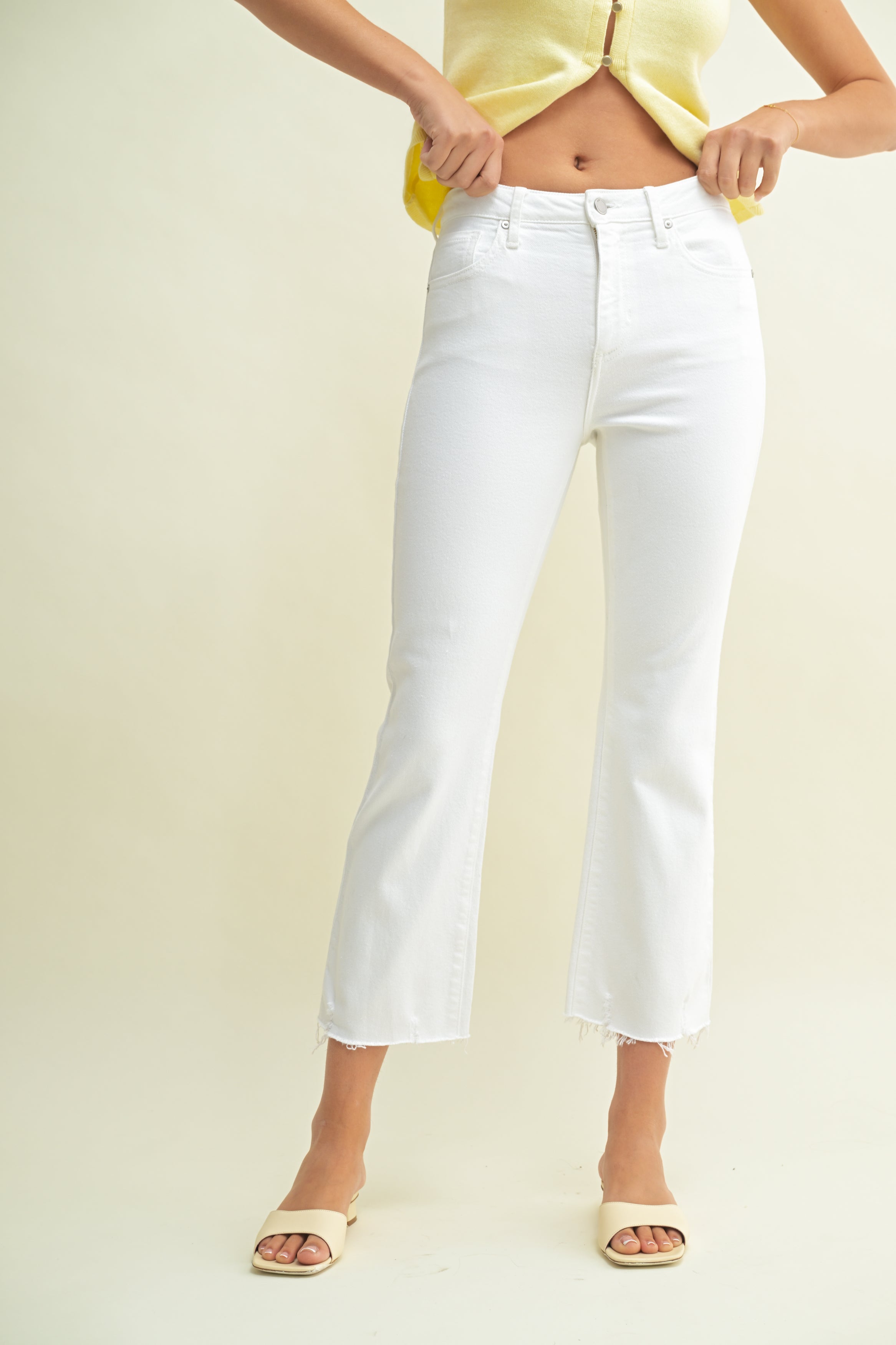 Person wearing white jeans and a yellow top on a plain background