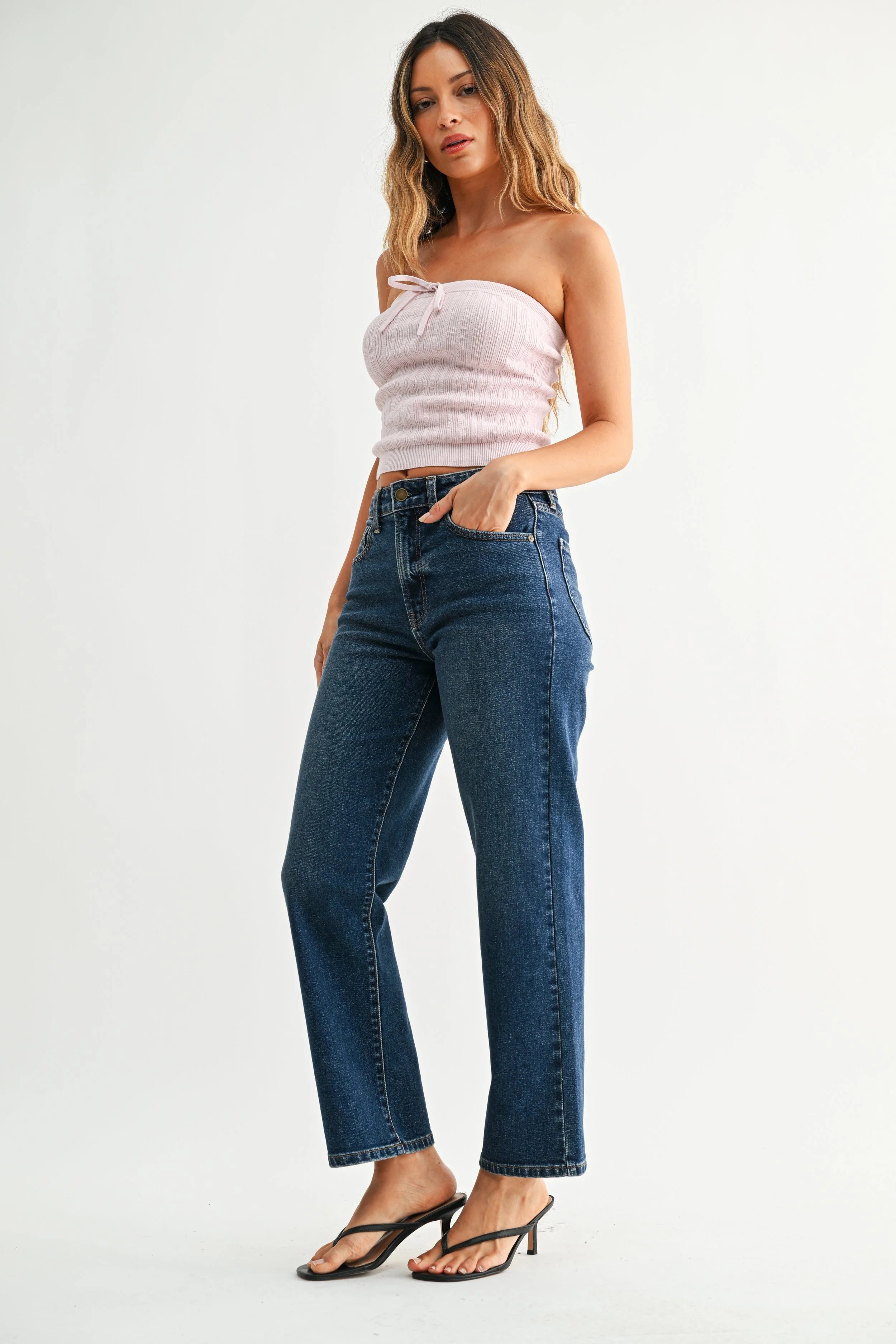 Woman wearing a strapless top and blue jeans on a white background