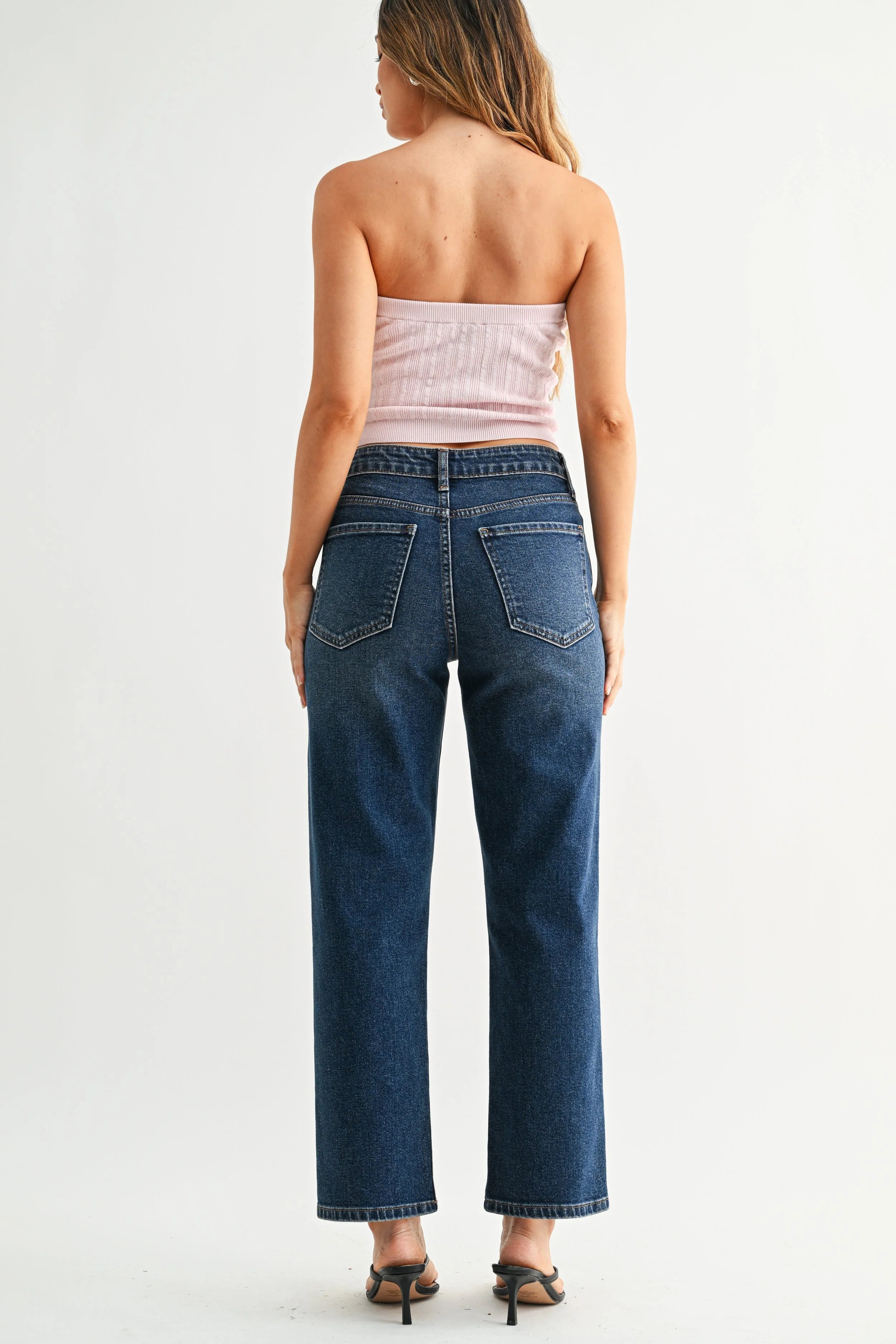 Woman wearing blue jeans and a strapless top on a white background