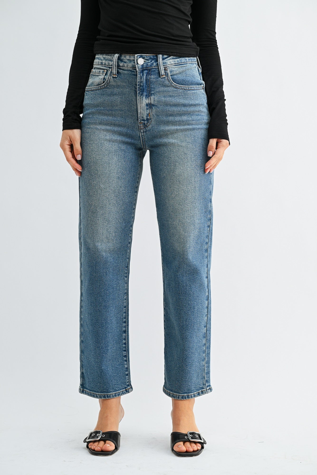 Person wearing blue jeans and a black top on a white background