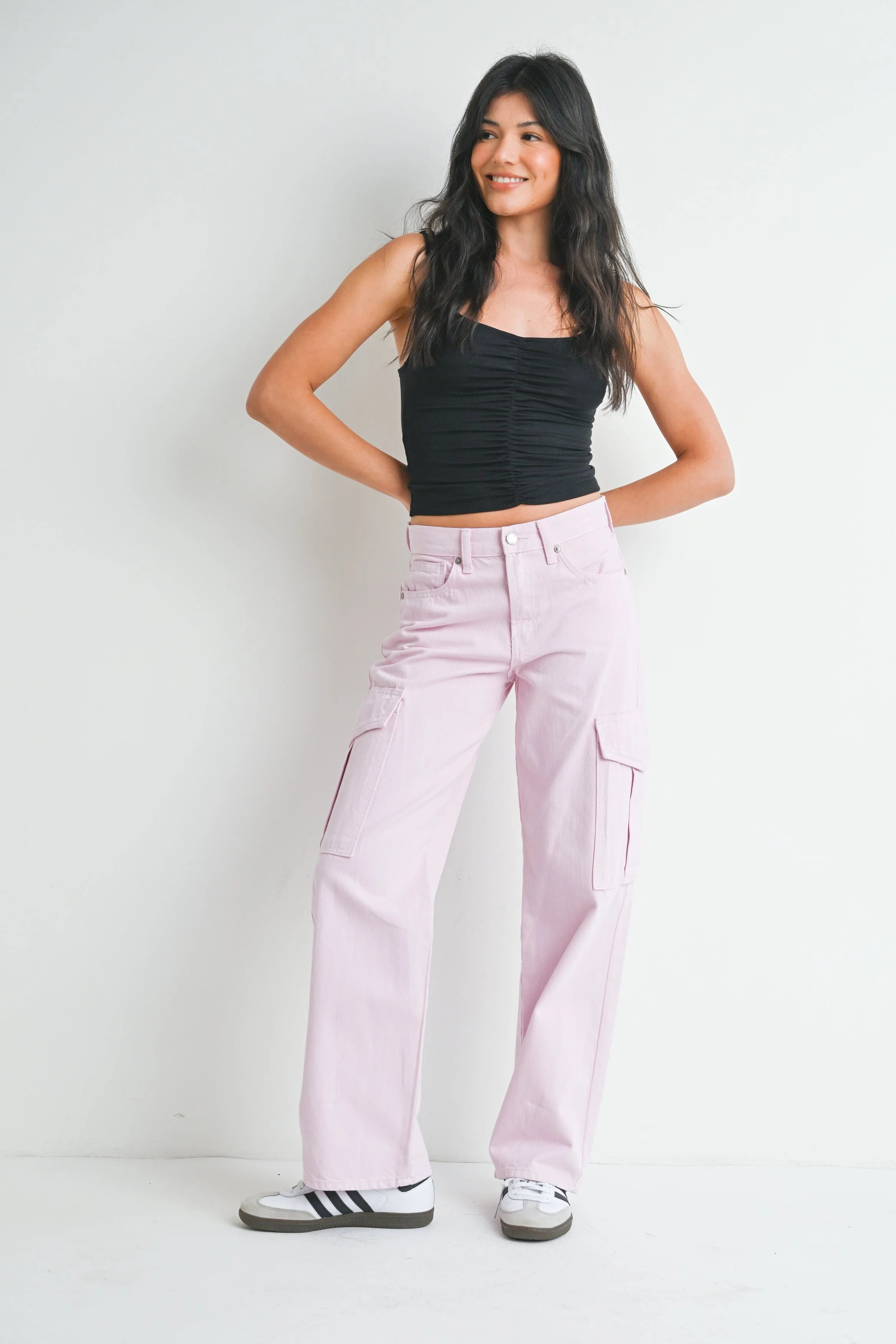 Woman wearing a black tank top and pink pants on a white background