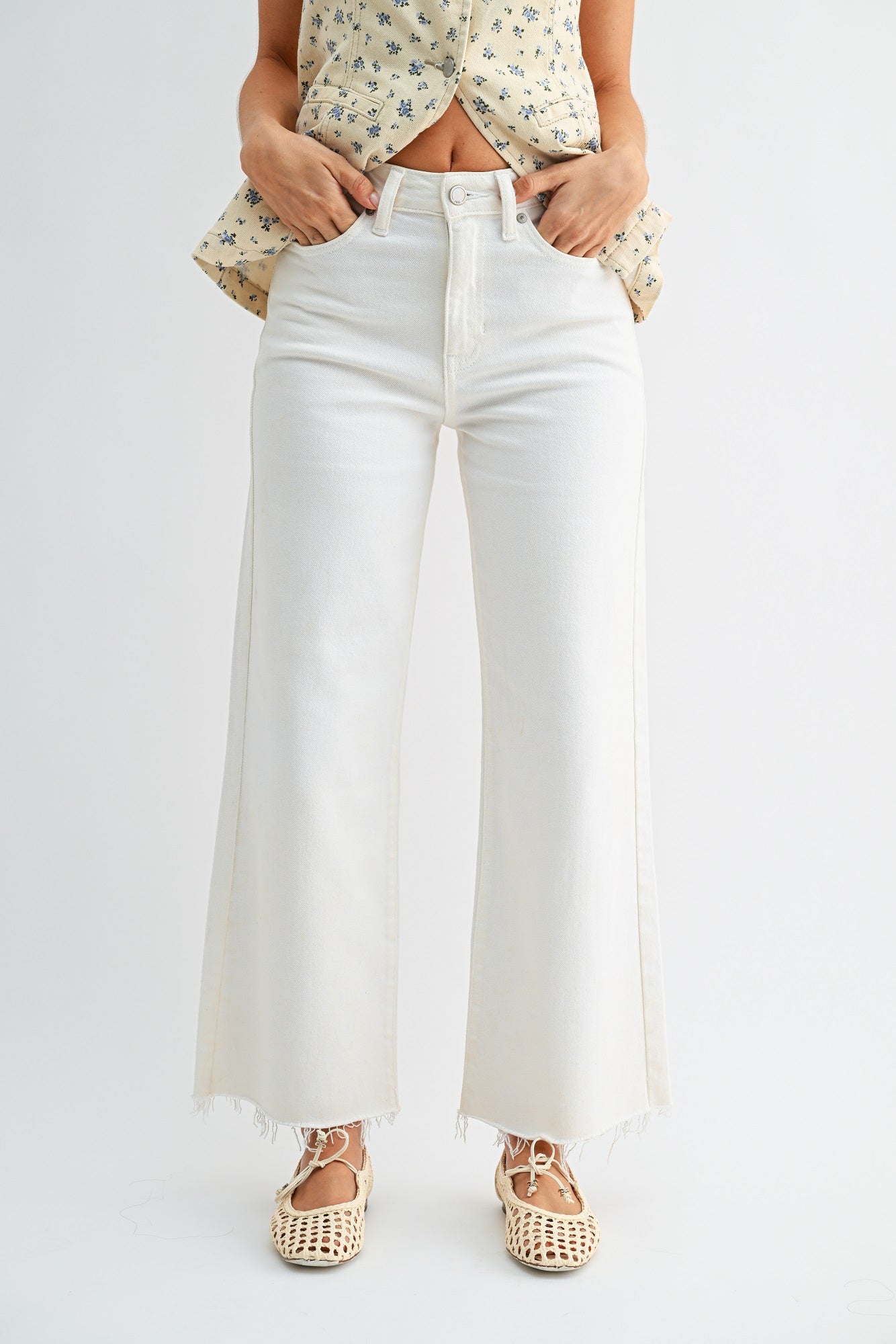 Person wearing white wide-leg jeans with a plain background