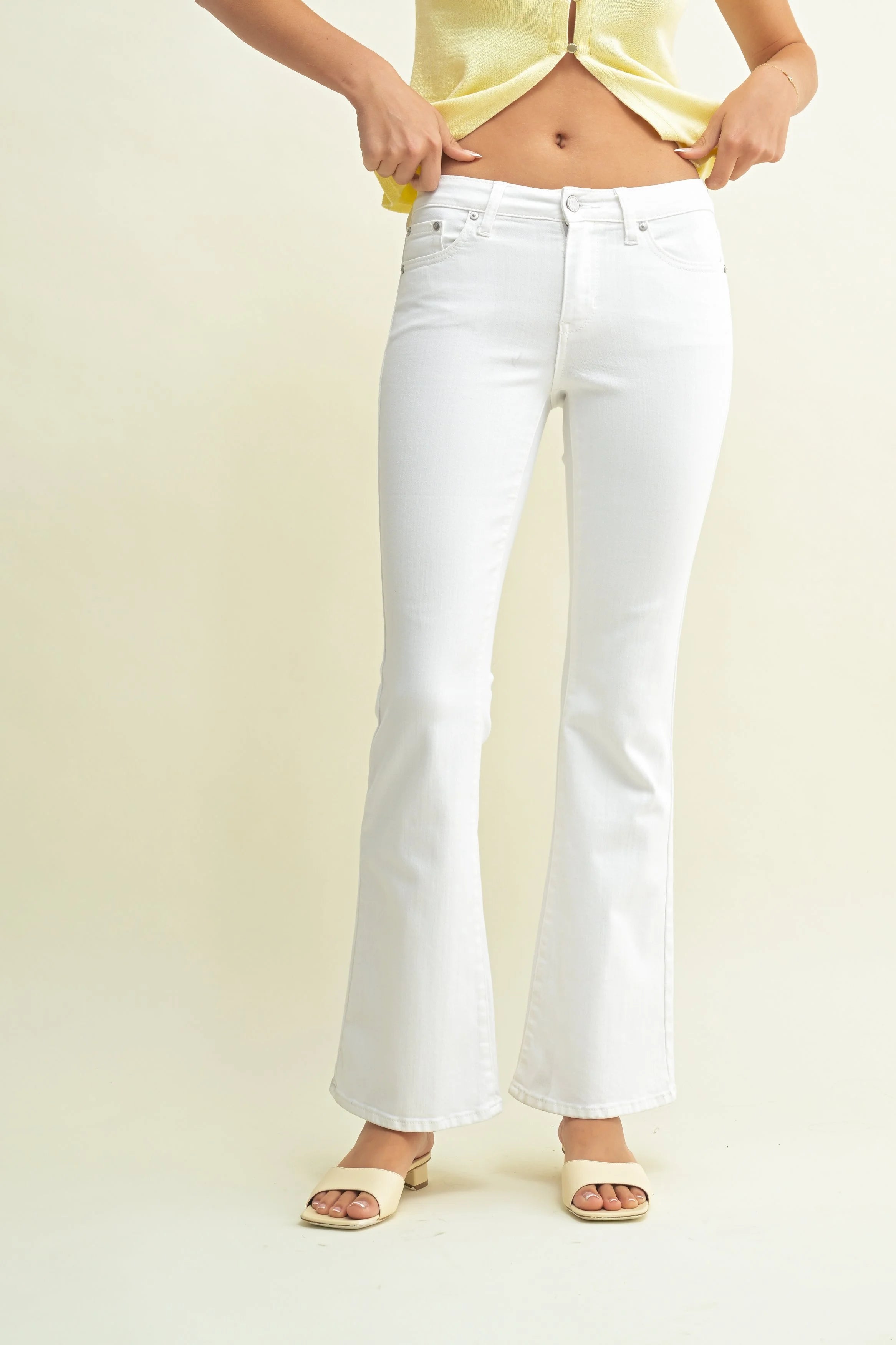 Person wearing white jeans and a yellow top on a plain background