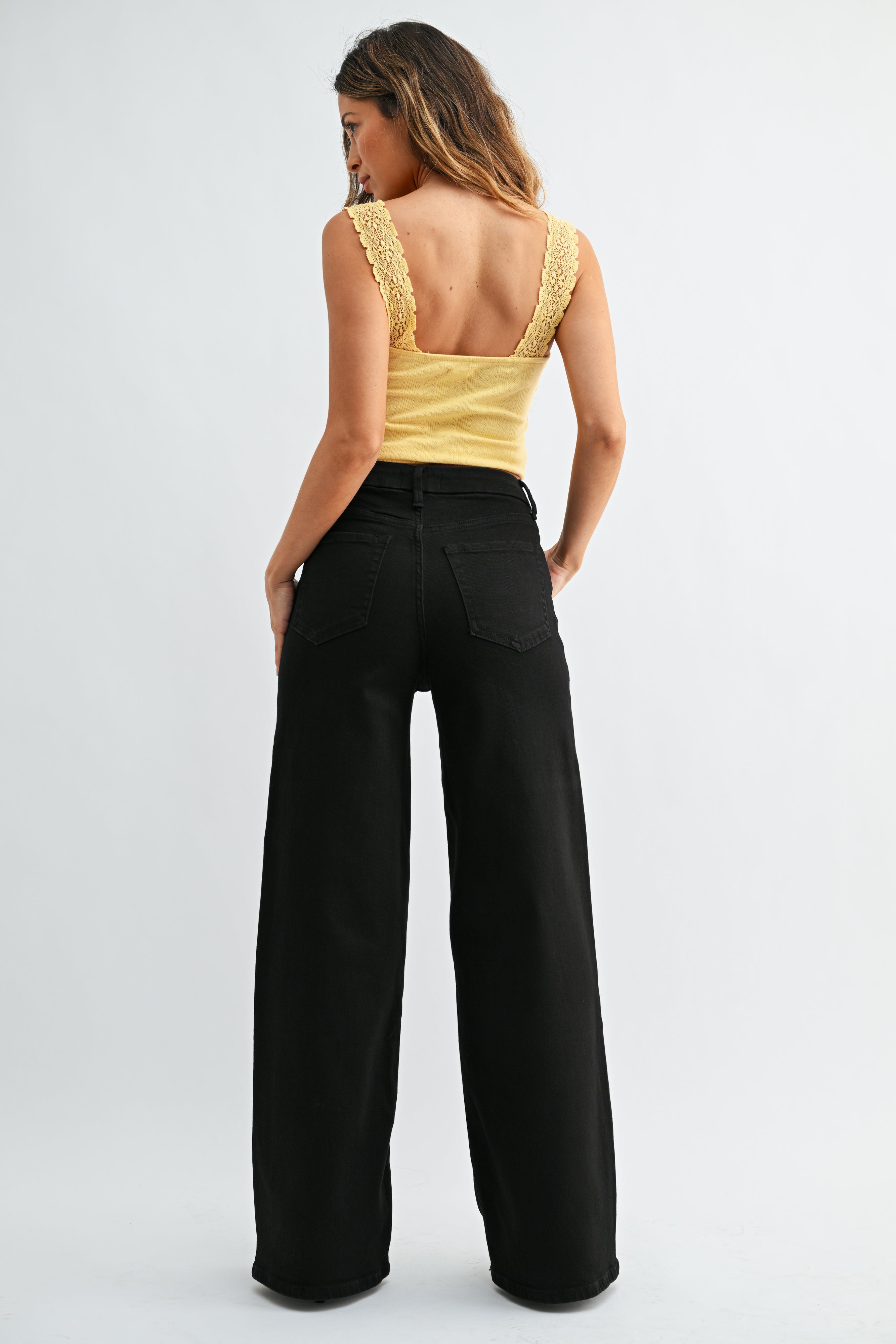 Woman wearing a yellow top and black pants on a white background
