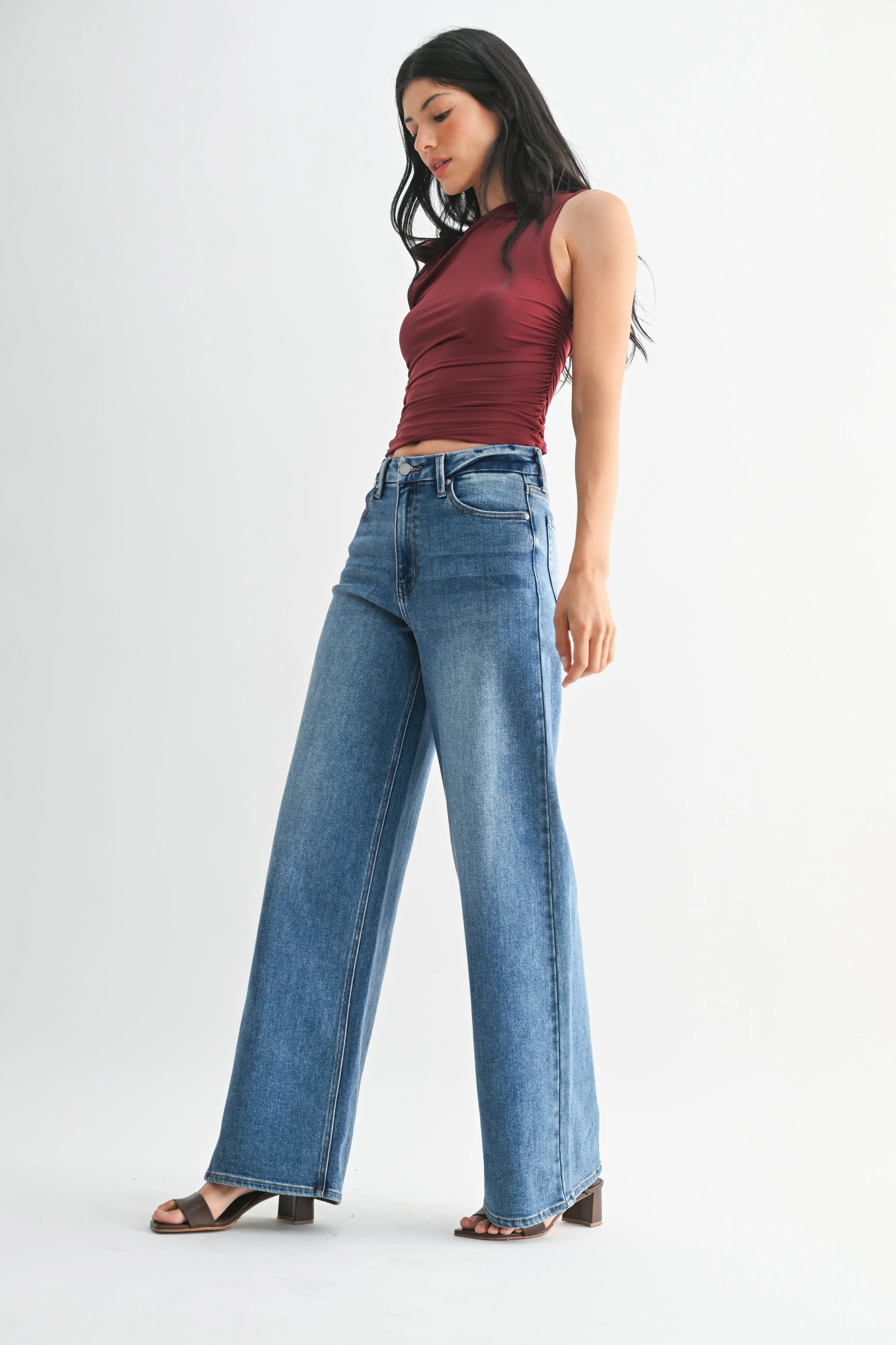 Woman wearing a red top and blue jeans on a white background