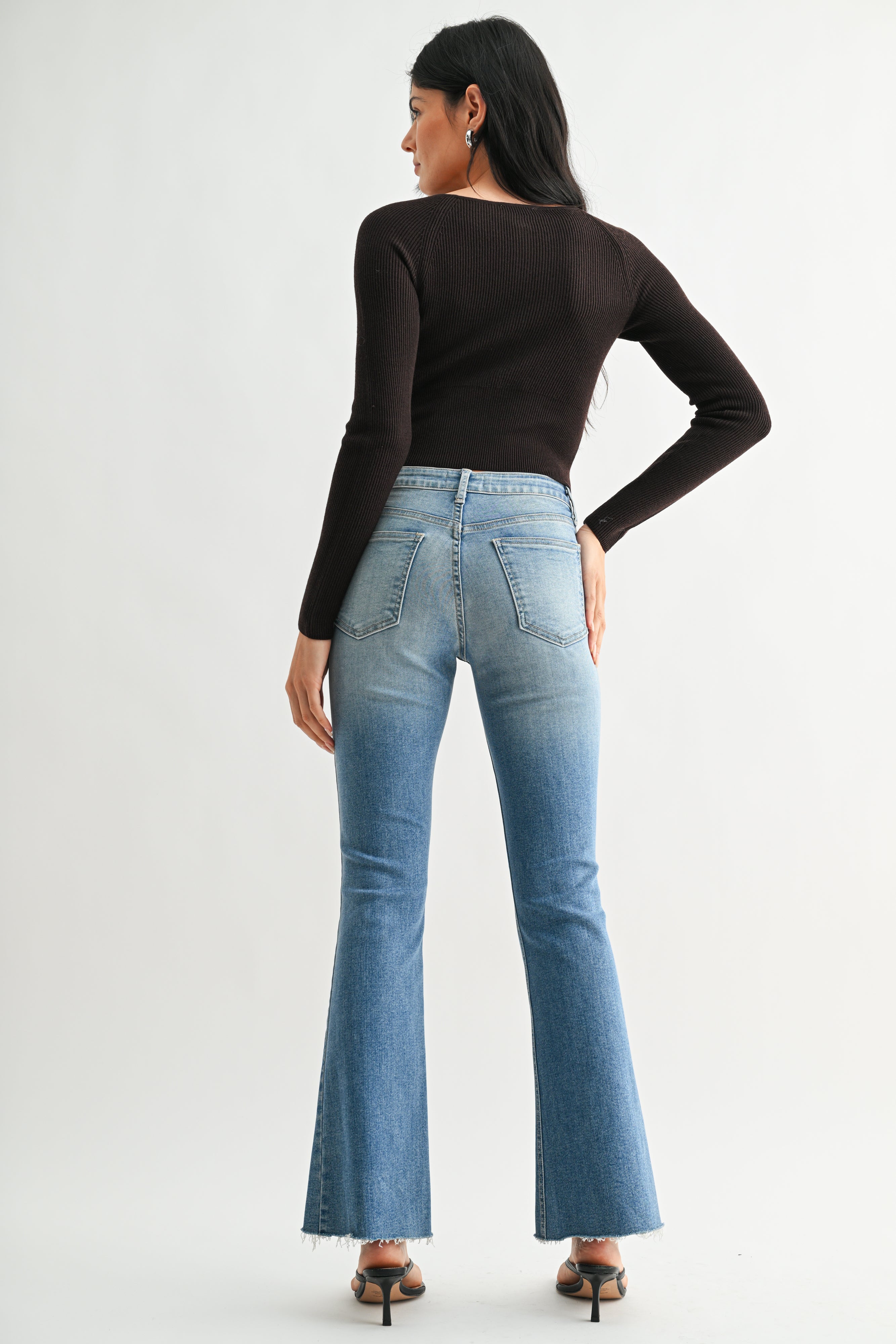Person wearing blue jeans and a black long-sleeve top on a white background