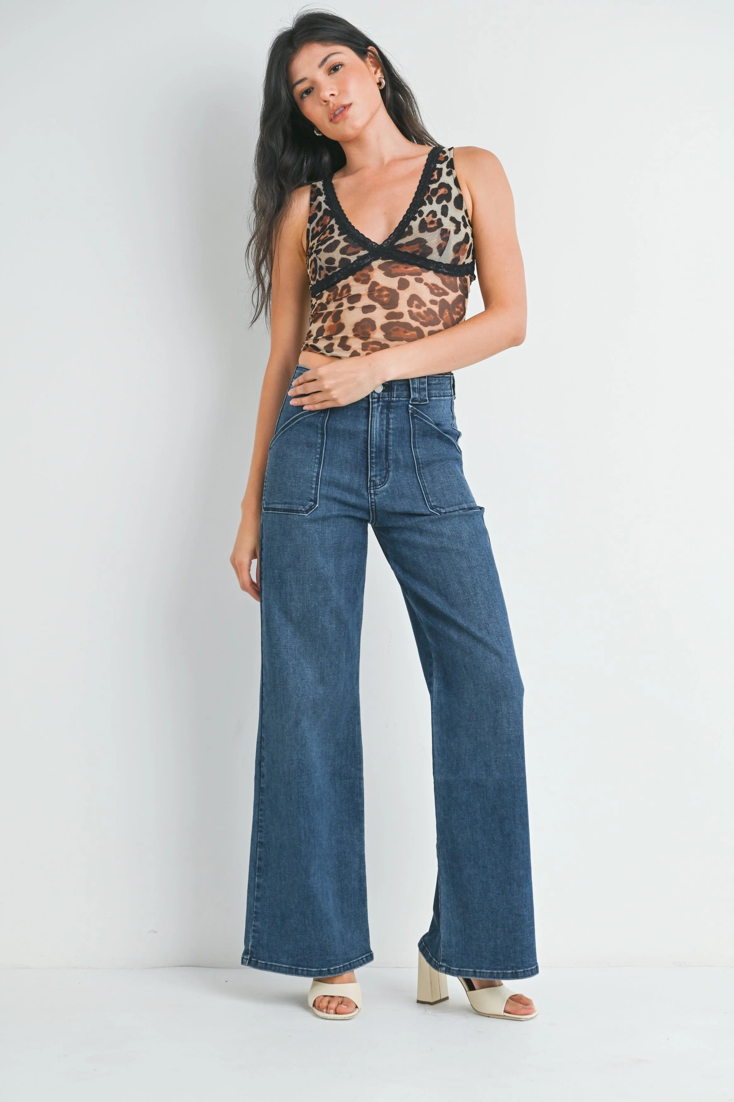 Woman wearing a leopard print top and blue jeans on a white background