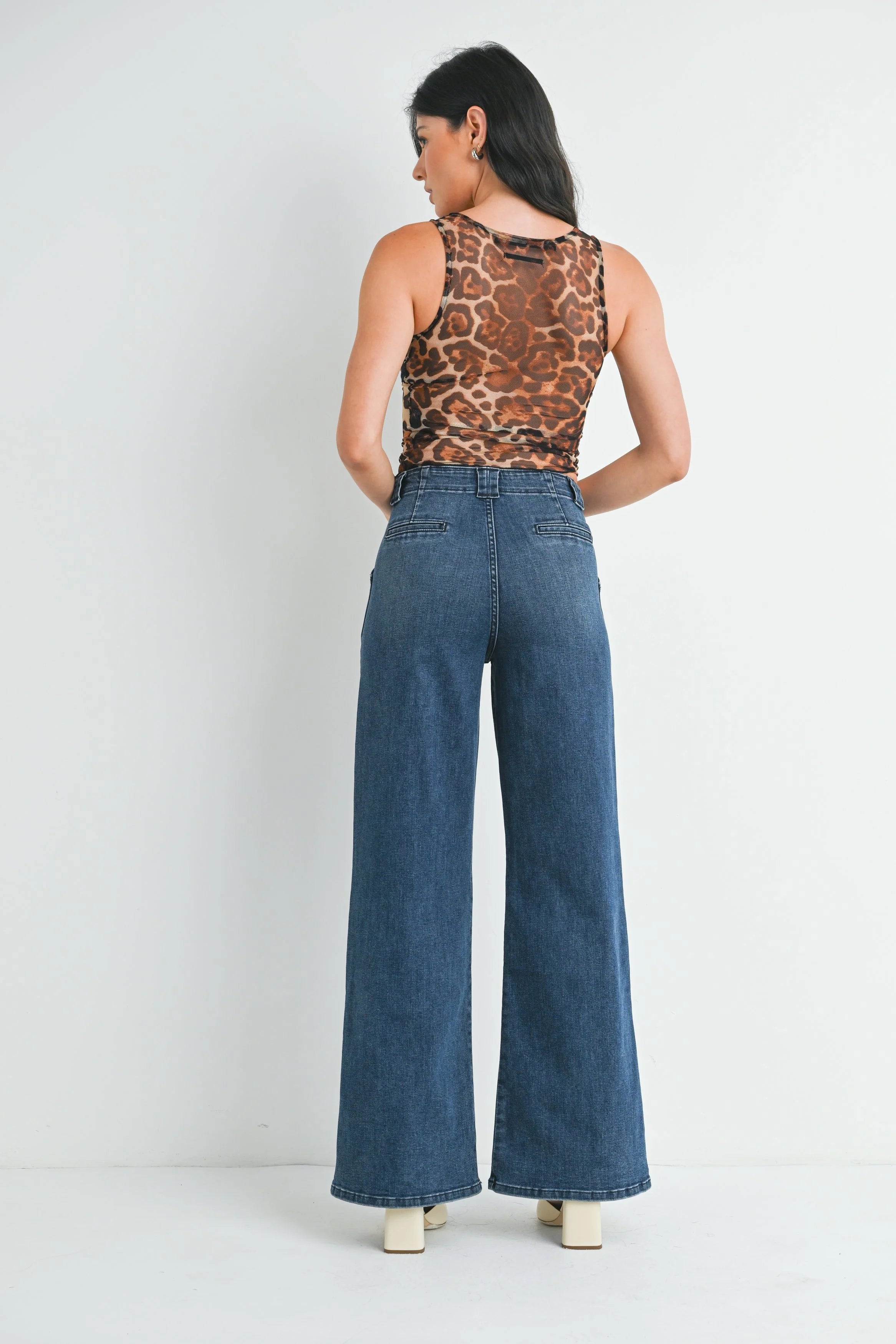 Woman wearing a leopard print top and blue jeans on a white background