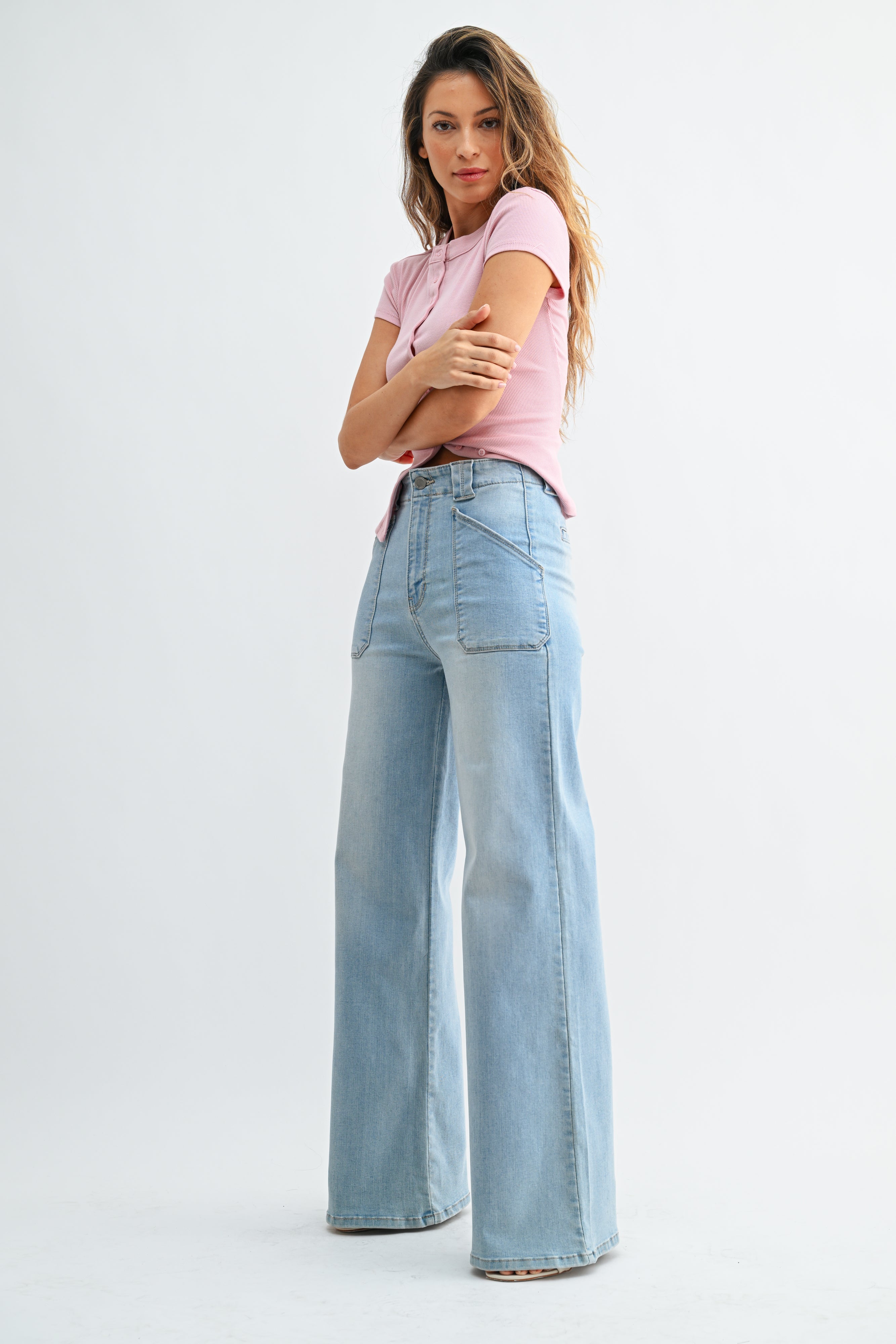 Woman wearing light blue jeans and a pink top on a white background