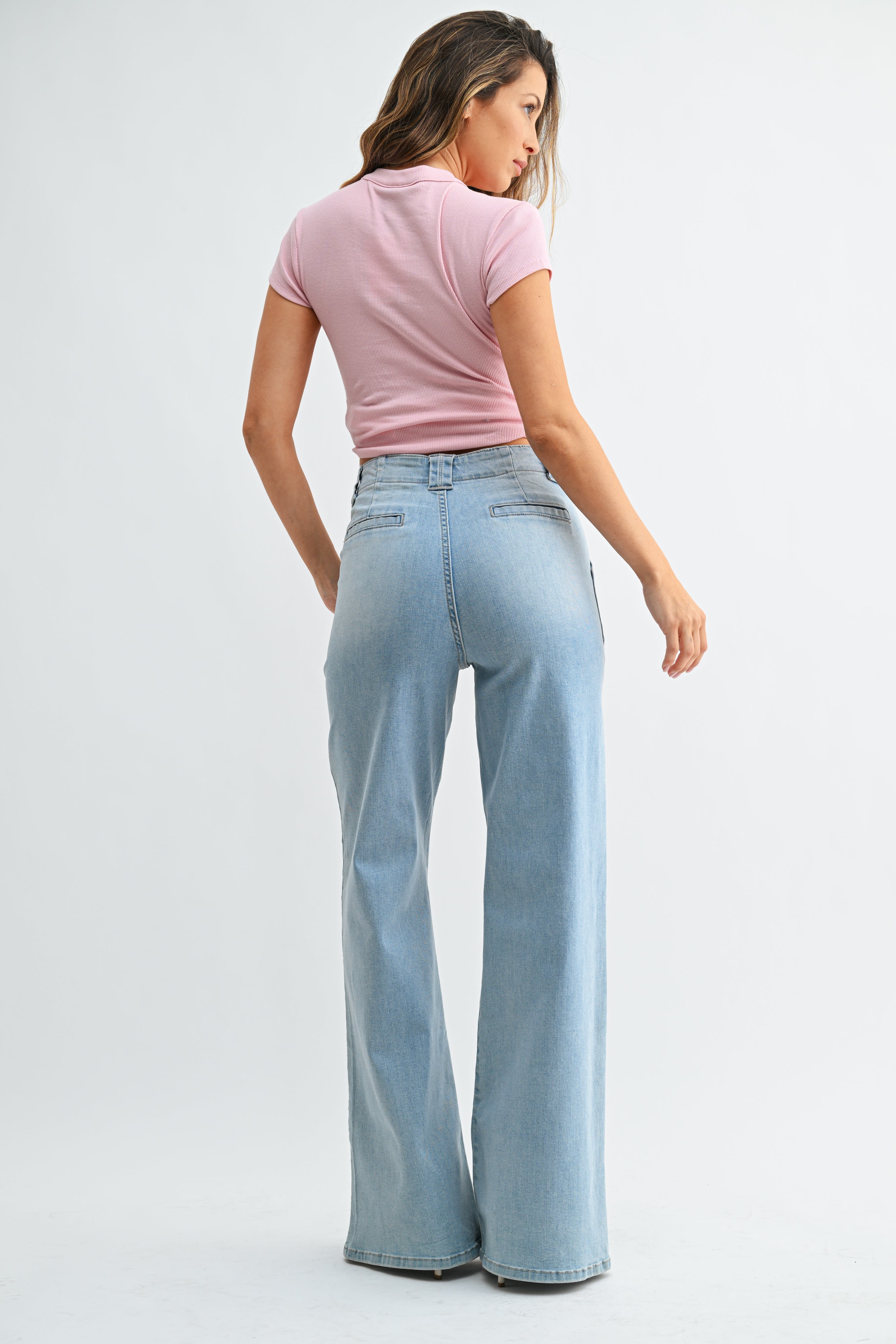 Woman wearing a pink top and light blue jeans on a white background