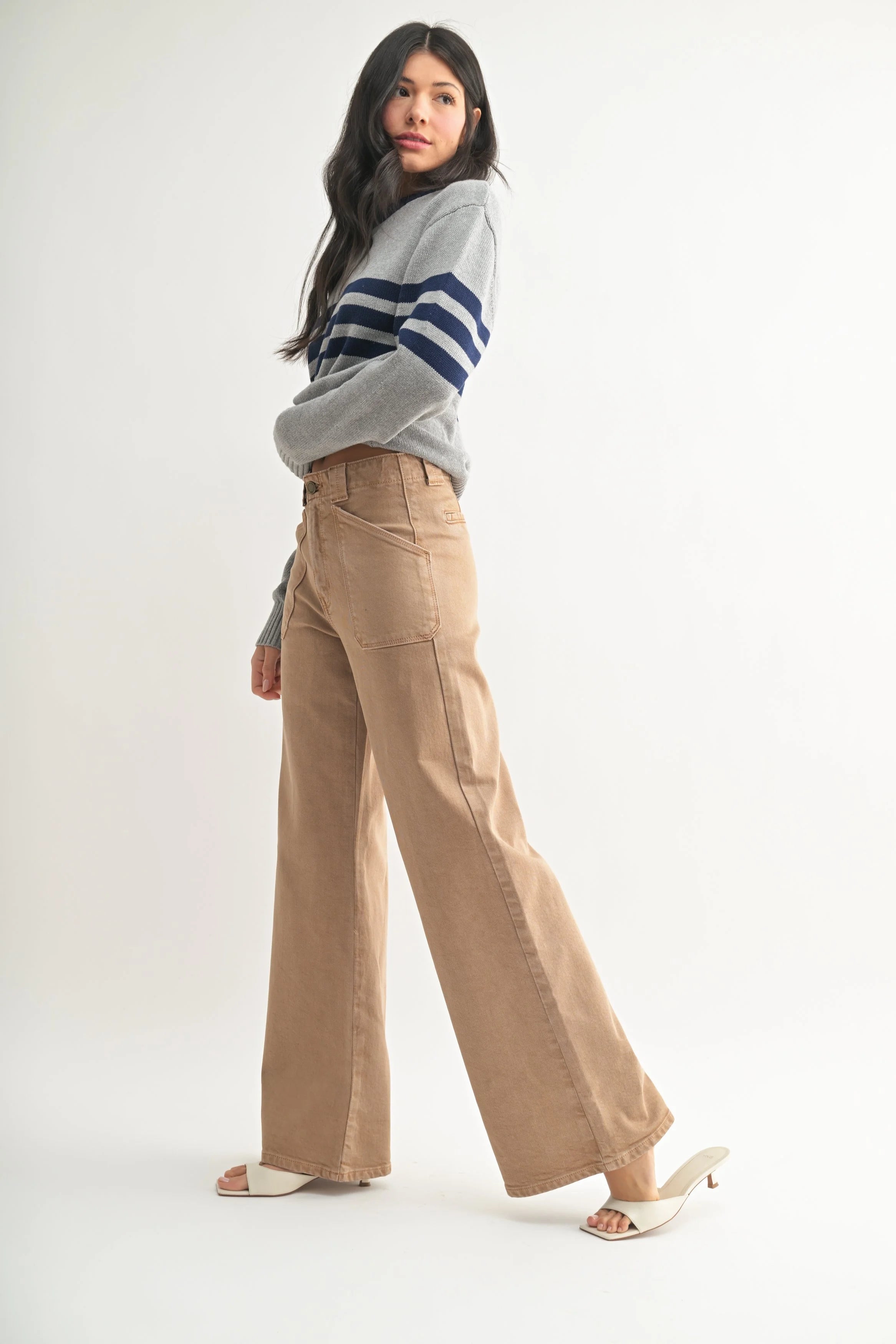 Woman wearing a striped sweater and beige pants on a white background