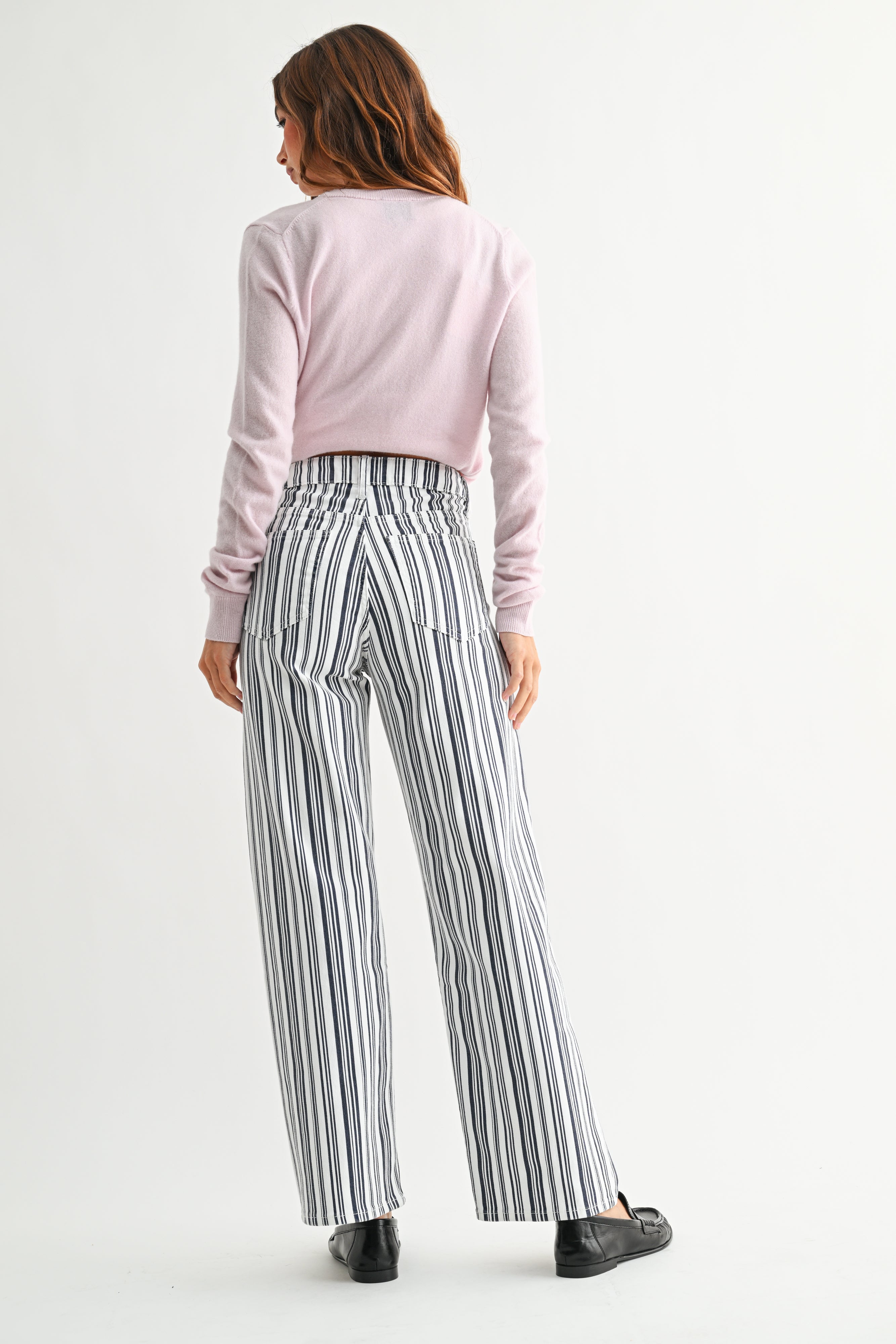 Woman wearing a pink top and striped pants on a white background