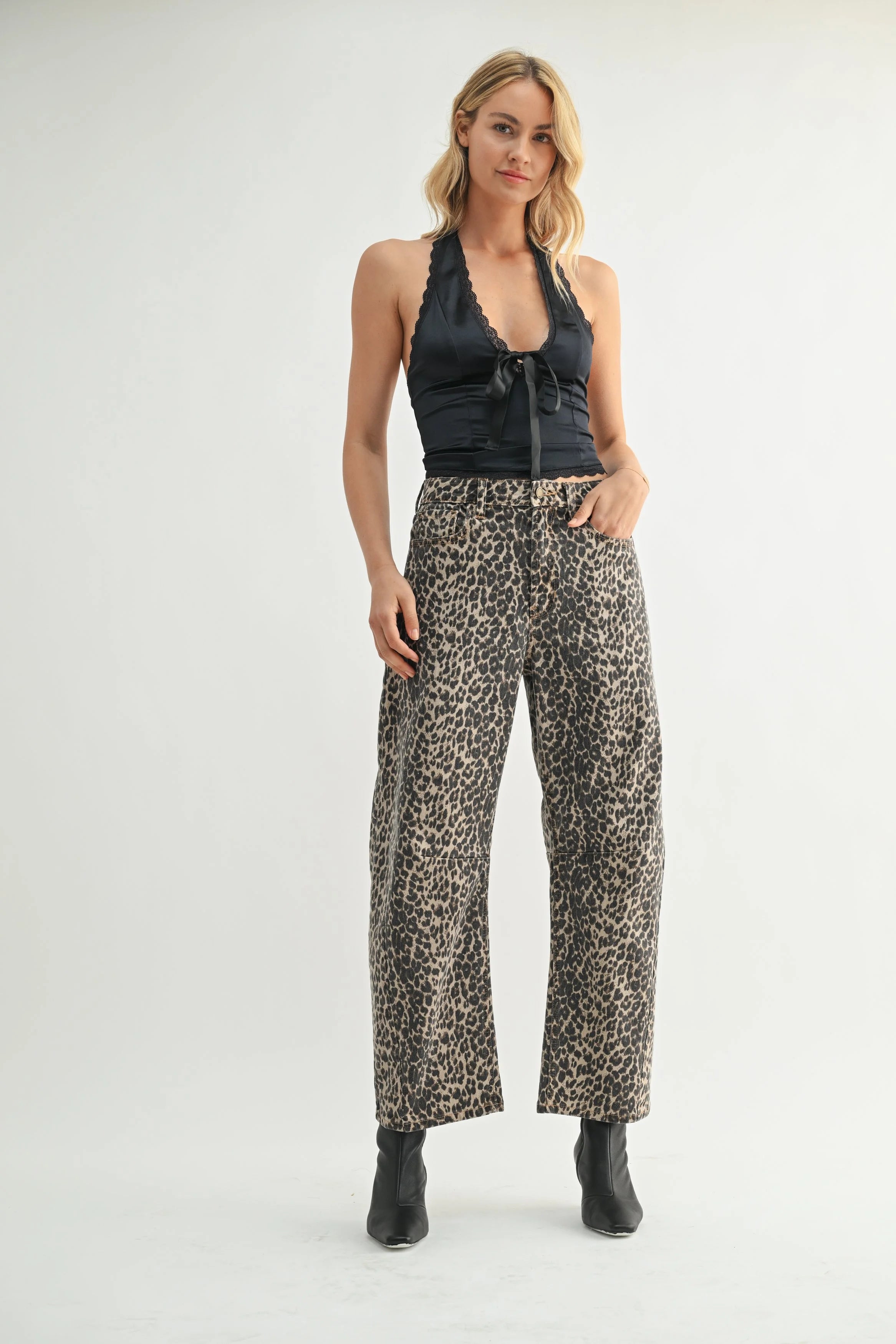 Woman wearing a black halter top and leopard print pants on a white background