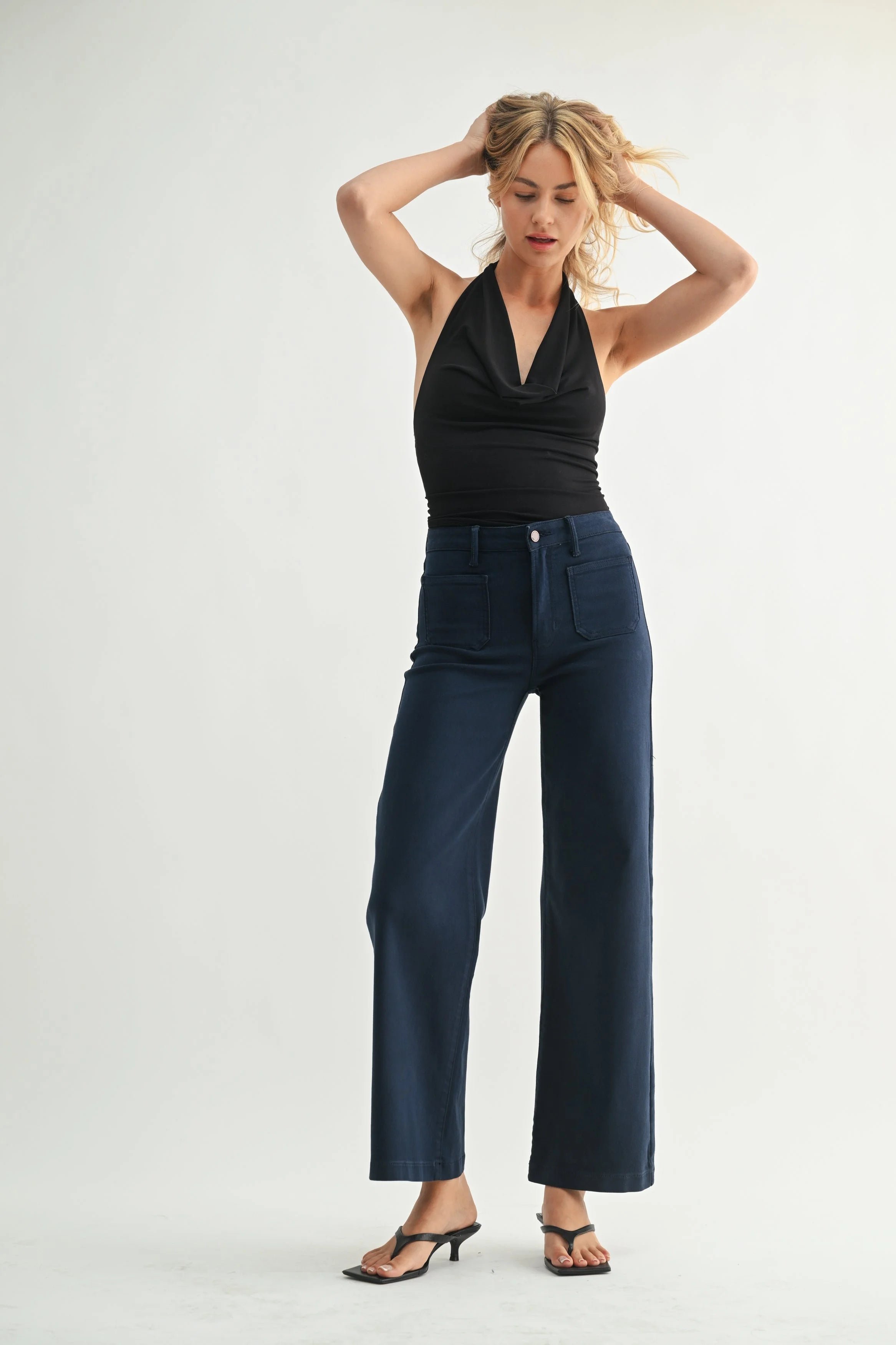 Woman wearing a black top and blue pants on a white background