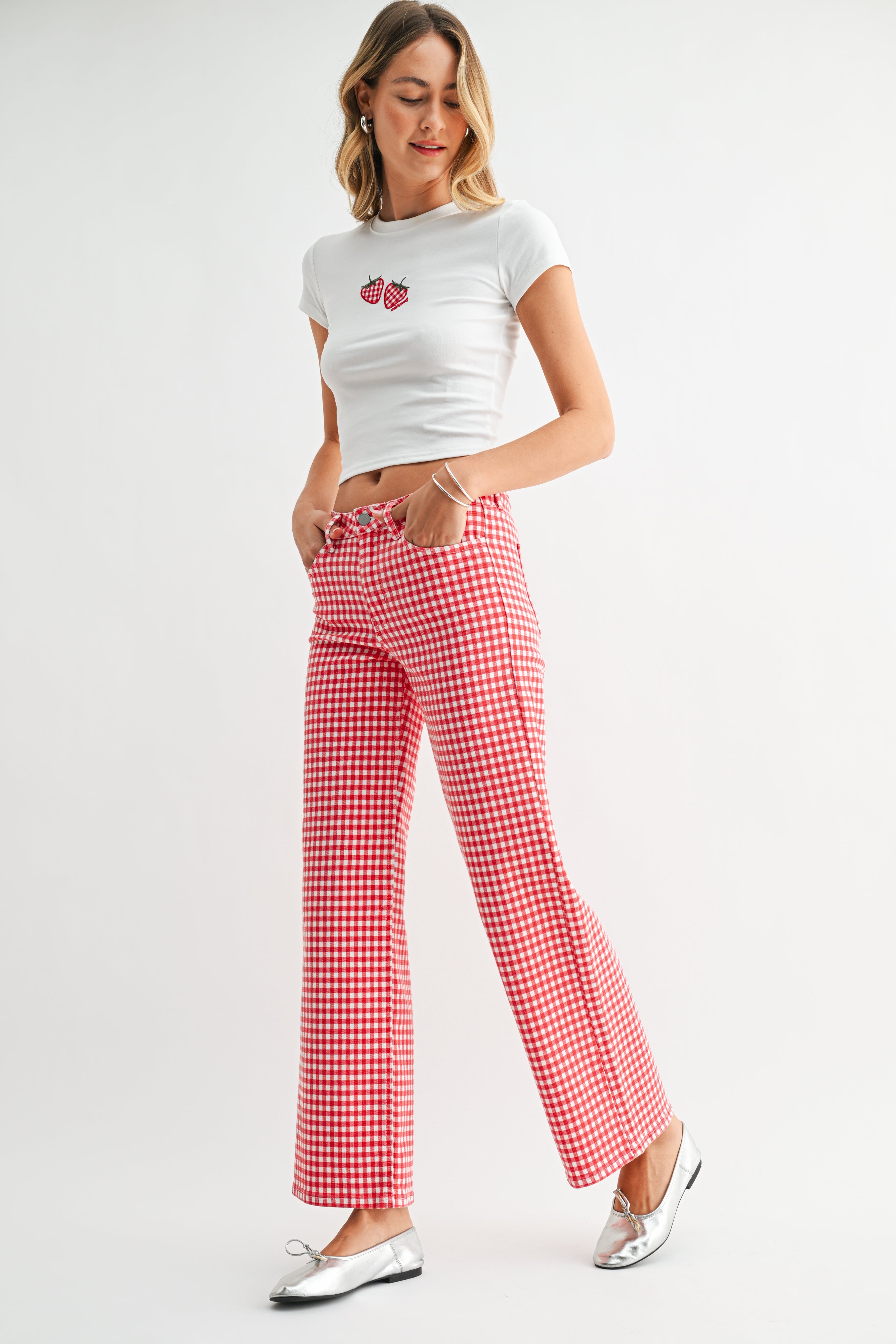 Woman wearing a white t-shirt with a red design and red checkered pants on a white background